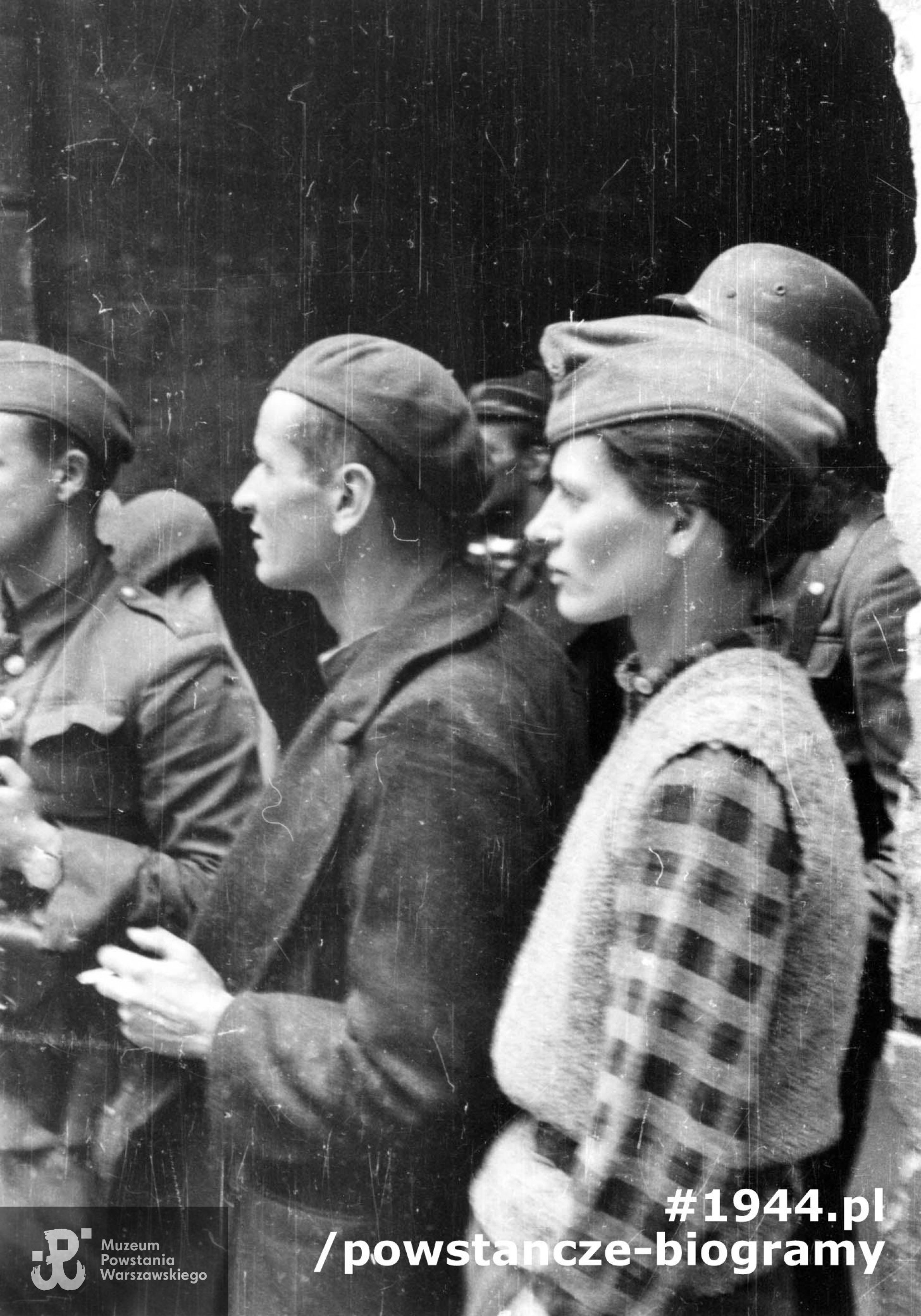Fotografia z Powstania Warszawskiego. Śródmieście Północne. Grupa powstańców z kompanii "Koszta" przed bramą (prawdopodobnie) na podwórzu kamienicy przy ul. Moniuszki 7. Od prawej: Zofia Domańska "Zocha" oraz mjr Stefan Mich "Kmita". Autorem zdjęcia jest Eugeniusz Lokajski "Brok". Fot. ze zbiorów Muzeum Powstania Warszawskiego, sygn. MPW-IN/822