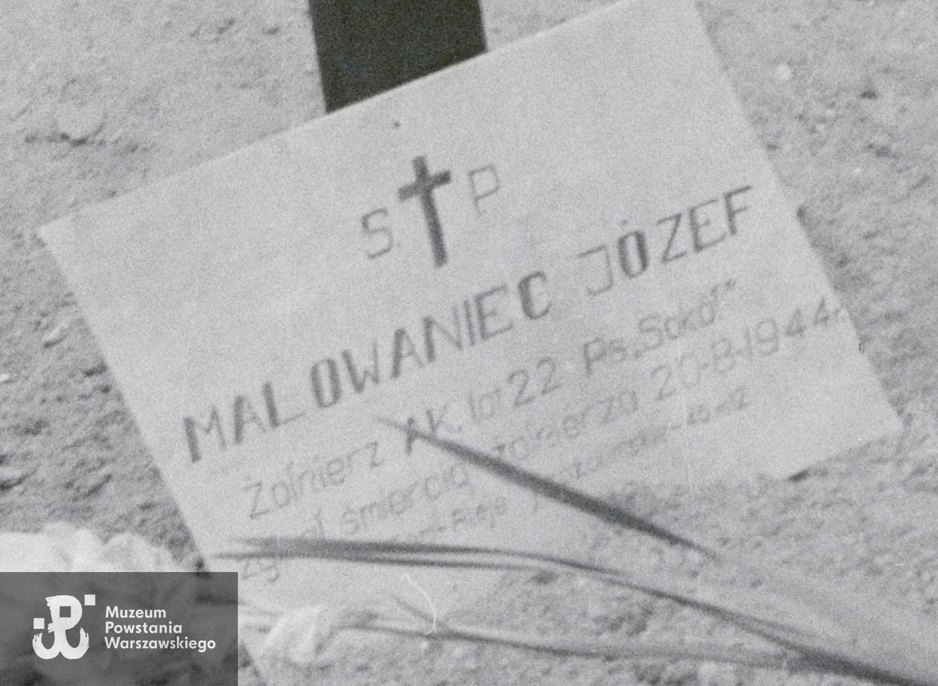 Fotografia z Powstania Warszawskiego (powiększony fragment) przedstawiająca mogiłę powstańczą kpr. Józefa Malowańca "Sokoła" z kompanii "Koszta" na chodniku pod kamienicą Jankowskiego przy ul. Moniuszki 12. Autorem zdjęcia jest Eugeniusz Lokajski "Brok", sygn. MPW-IN/688