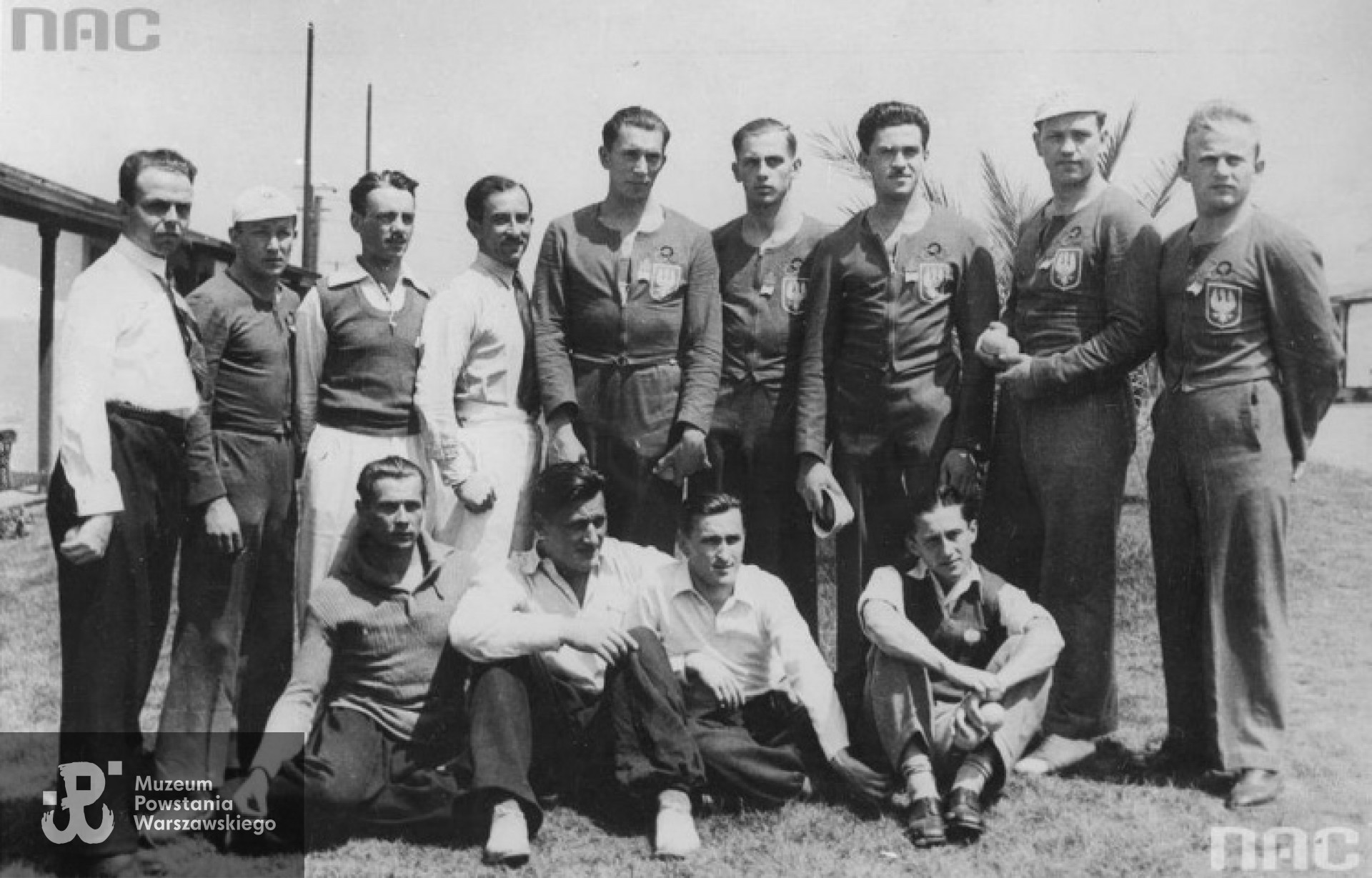 Grupa polskich sportowców w wiosce olimpijskiej w Baldwin Hills. Widoczni od lewej, stoją: szermierz Tadeusz Friedrich, wioślarz Jan Mikołajczak, szermierze: Marian Suski i Władysław Dobrowolski; wioślarze: Janusz Ślązak, Jerzy Braun, Edward Kobyliński, Stanisław Urban, Henryk Budziński. Siedzą, od lewej: lekkoatleci: Zygmunt Siedlecki (wieloboista), Zygmunt Heljasz, Janusz Kusociński (złoty medal za bieg na 10 000 m) i sternik Jerzy Skolimowski. Brązowy medal dla szermierzy w konkurencji: szabla otrzymali: W. Dobrowolski, T. Friedrich, M. Suski. Srebrny medal dla wioślarzy za dwójki ze sternikiem otrzymali: J. Braun, J. Ślązak, J. Skolimowski. Brązowy medal dla wioślarzy za dwójki bez sternika otrzymali: J. Mikołajczak, H. Budziński. Brązowy medal za czwórki ze sternikiem otrzymali: J. Braun, E. Kobyliński, St. Urban, J. Ślązak, J. Skolimowski / fot. Koncern Ilustrowany Kurier Codzienny - Archiwum Ilustracji, nac.gov.pl