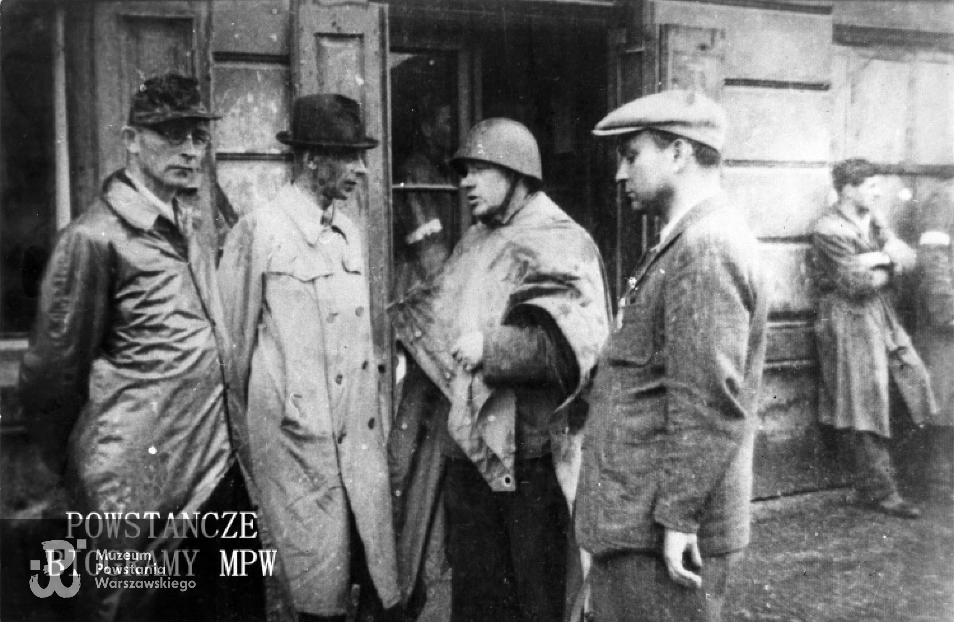 Fotografia z Powstania Warszawskiego. Wola. Inspekcja oddziałów "Radosława" w okolicach ul. Mireckiego. Od lewej : mjr  Wacław Janaszek "Bolek" (szef sztabu "Radosława"), gen. Tadeusz Komorowski "Bór", płk Jan Mazurkiewicz "Radosław" i kpt. Ryszard Krzywicki "Szymon" (adiutant "Bora"). Fot. ze zbiorów Muzeum Powstania Warszawskiego, sygn. MPW-IK/1267