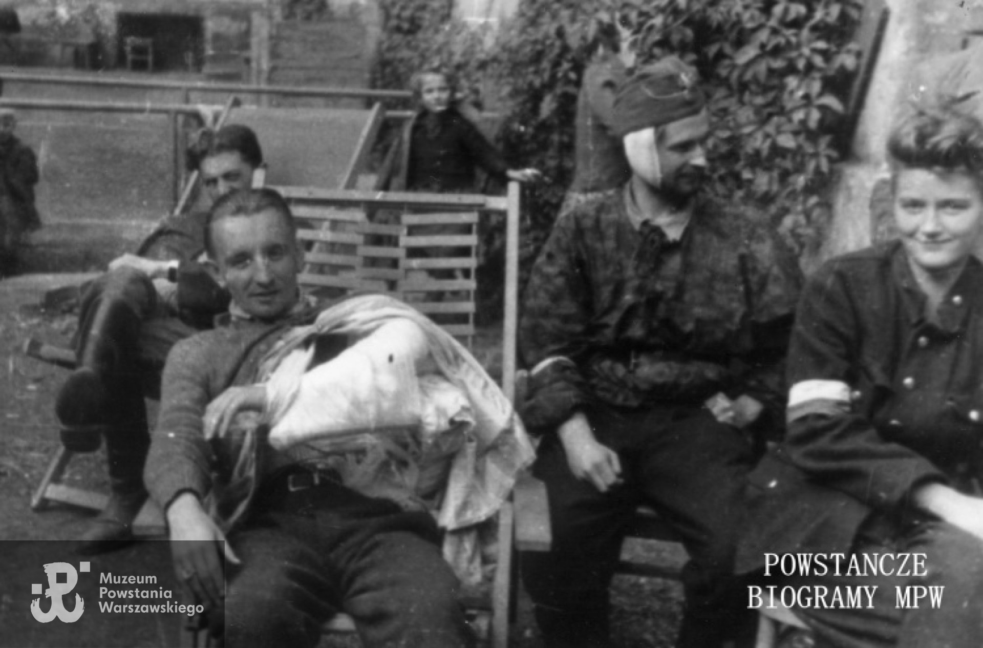 Fotografia z Powstania Warszawskiego. Śródmieście Południowe, ul. Śniadeckich. Ranni żołnierze batalionu "Chrobry I" w szpitalu polowym   przy ul. Śniadeckich 17 (ewakuowany z ul. Senatorskiej Szpital Maltański).  Drugi od lewej ppor. "Marek", trzeci pchor. "Stanisław Ptaszyński "Skała", pierwsza z prawej - łączniczka Krystyna Zapaśnik "Krystyna". Autor fot. Zygmunt Sowiński "Ostoja". Ze zbiorów Muzeum Powstania Warszawskiego, sygn. MPW-IP/7205