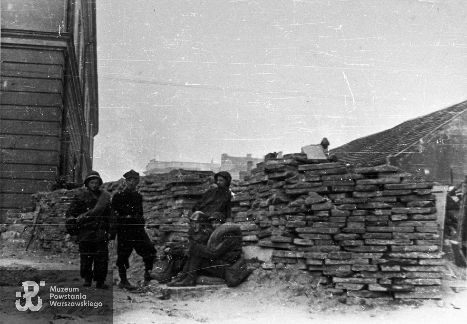 Fotografia z Powstania Warszawskiego. Stare Miasto, ul. Nalewki. Powstańcy z batalionu "Chrobry I" na barykadzie przy Arsenale. Drugi od lewej stoi por. Eugeniusz Glass-Brudziński "Marek", pierwszy od lewej siedzi strz. Bronisław Borowski "Słowik. Fot. ze zbiorów Muzeum Powstania Warszawskiego, sygn. MPW-IN/86972. Autorem zdjęcia jest Zygmunt Sowiński "Ostoja"