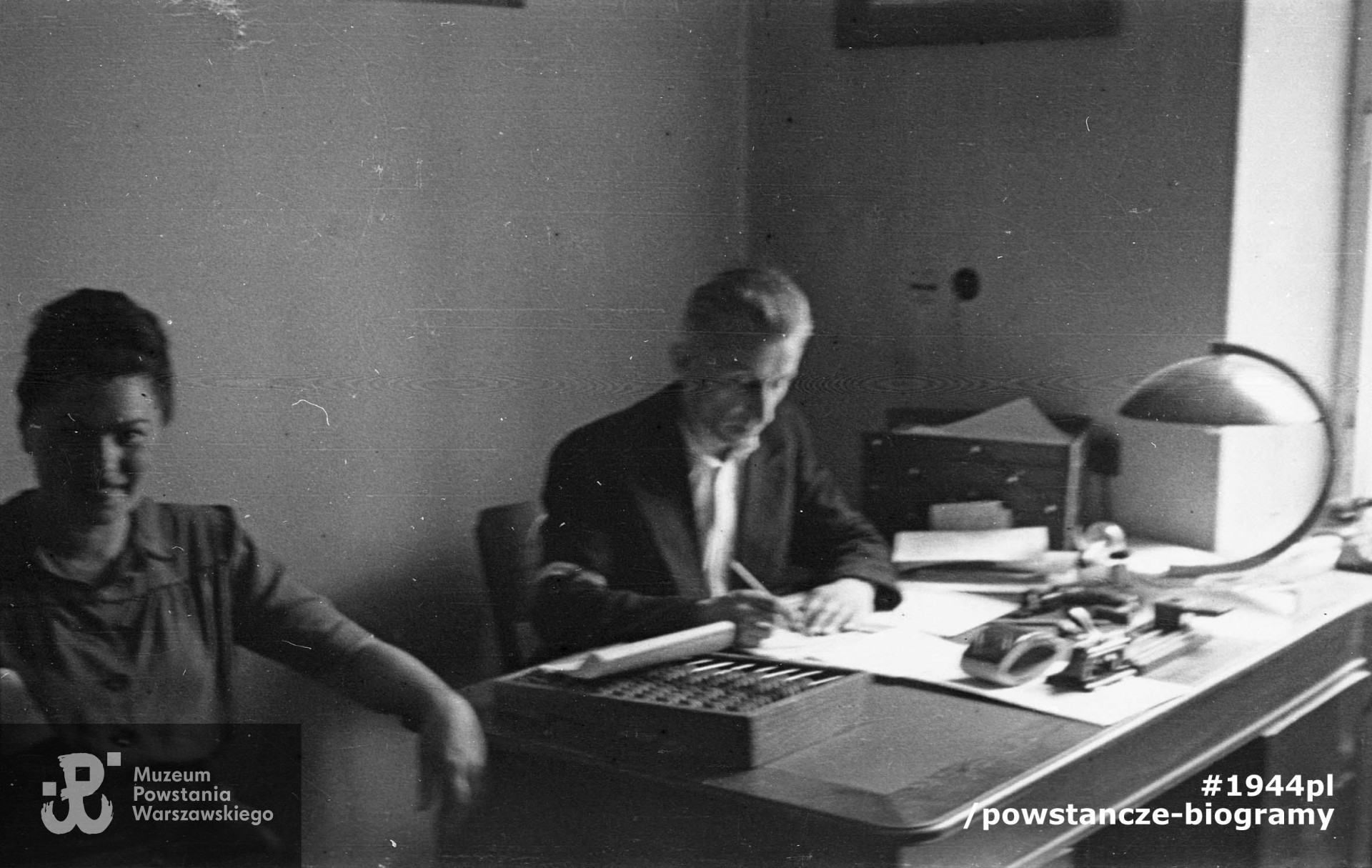 Mjr.  Zbigniew Jagniątkowski "Lubicz" z Korpusu Bezpieczeństwa przy pracy biurowej, obok łączniczka "Madzia". Prawdopodobnie w lokalu KB na ul. Boduena 3. Fotografia z Powstania Warszawskiego autorstwa Mariana Grabskiego "Wyrwy". Fot. ze zbiorów Muzeum Powstania Warszawskiego, sygn. MPW-IN/1675