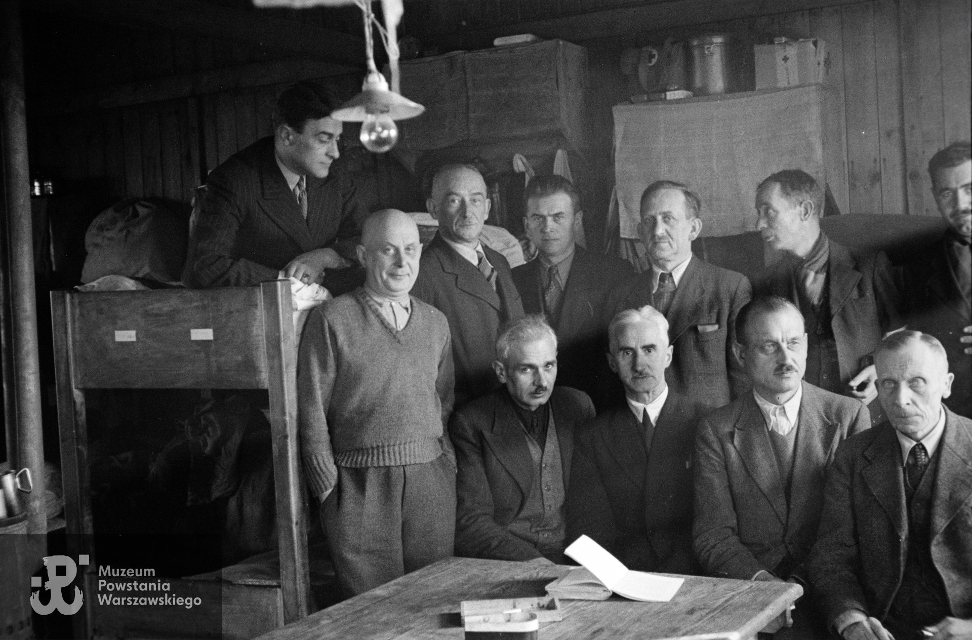 Fotografia z Polskiego Szpitala Wojskowego w saksońskim Zeithain. Lekarze w baraku 14. Na pryczy dr Zdzisław Januszewski. Stoją od lewej: por. Jan Sawczak „Knihinicki", płk dr dr Leon Strehl „Feliks”, NN, dr Mieczysław Zapolski, dr Marian Mroczkowski, sanitariusz Józef Osipowicz. Siedzą: dr Stanisław Manczarski , mjr dr Tadeusz Kawecki „Lwowicz”. mjr dr Jan Durko „Dunin”, mjr dr Michał Grobelski „Doktor Zygmunt”. Autorem zdjęcia jest Czesław Gerwel „Orłoś”. Fot. ze zbiorów Muzeum Powstania Warszawskiego, sygn. MPW-IN/3792