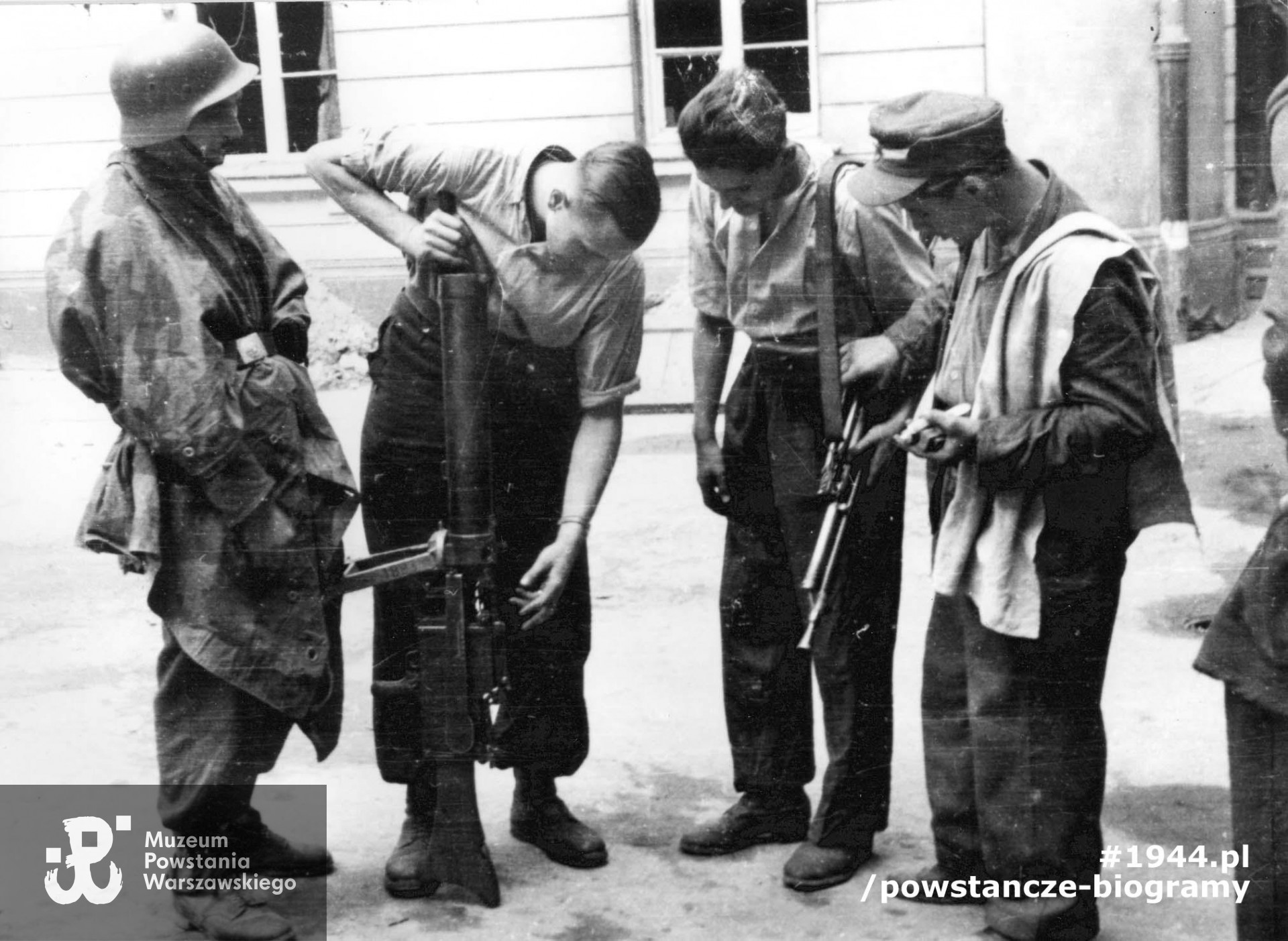 Fotografia z Powstania Warszawskiego. Śródmieście Północne. Podwórze kamienicy przy ul. Świętokrzyskiej 20. Plut. pchor. Adam Podkóliński "Michał", „Olszewski” prezentuje grupie powstańców z kompanii "Janusza" Batalionu "Harnaś" niemiecki lekki karabin maszynowy leMG 08/15 zdobyty po ataku na Komendę Policji. Drugi od prawej kpr. pchor. Włodzimierz Wiśniewski "Cygan" z czechosłowackim, ręcznym karabinem maszynowym ZB wz. 1926. Fot. ze zbiorów Muzeum Powstania Warszawskiego, sygn. MPW-IN/722. Autorem zdjęcia jest Eugeniusz Lokajski "Brok".