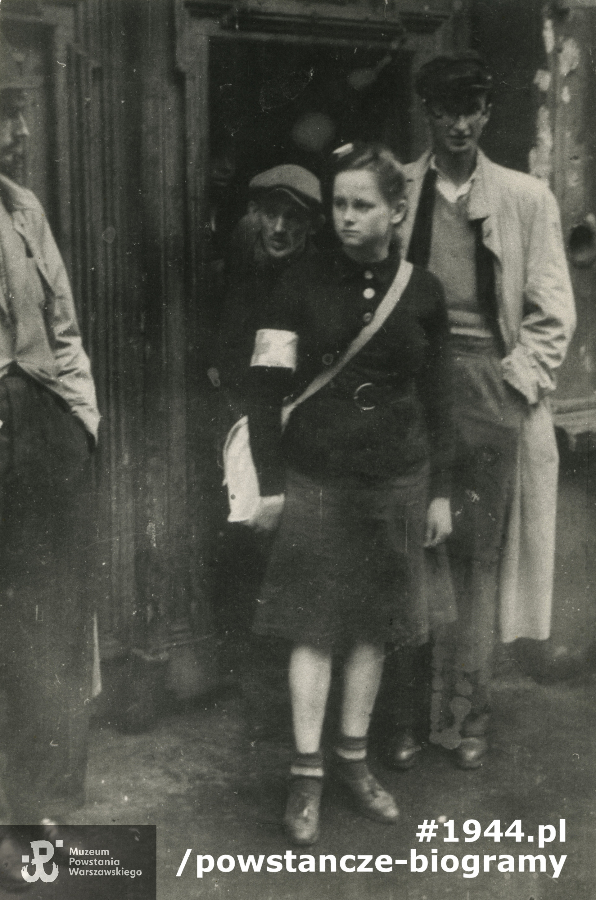 Fotografia z Powstania Warszawskiego. Śródmieście Północne. Sanitariuszka Barbara Otwinowska "Błękitny Witek", "Baśka" z 100. kompanii sztabowej Zgrupowania "Bartkiewicz" przed bramą domu przy ul. Siennej 19. Autorem zdjęcia jest  Stefan Antoni Koper "Nienaski", PSW. Fot. ze zbiorów Muzeum Powstania Warszawskiego, sygn. MPW-IP/4085