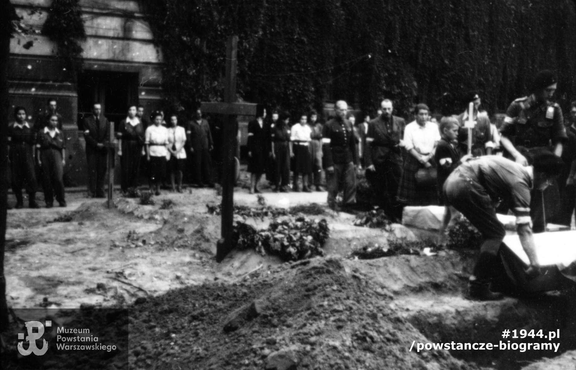 Fotografia z Powstania Warszawskiego. Pogrzeb powstańczy na dziedzińcu budynku Wydziału Architektury Politechniki Warszawskiej przy ulicy Lwowskiej 12 róg Koszykowej. Na drugim planie nad mogiłą stoją: kpt. Stefan Golędzinowski "Golski" z żoną Alicją. Fot. ze zbiorów Muzeum Powstania Warszawskiego, sygn. MPW-IP/5354-24