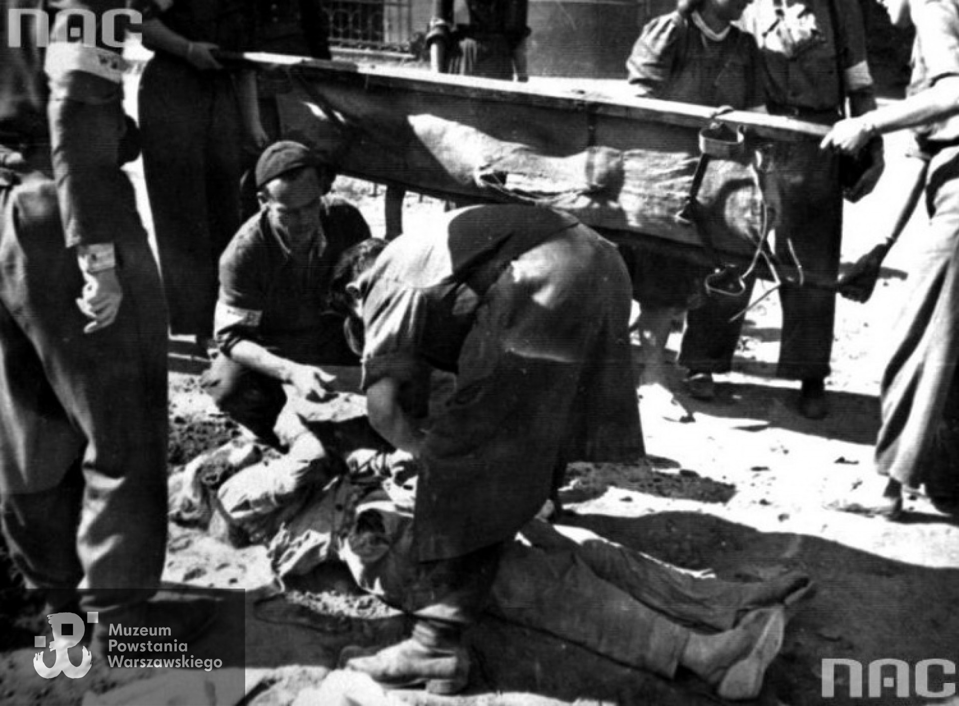 28 sierpnia 1944 roku:  pochówek ofiar ostrzału artyleryjskiego zasypanych w Filharmonii Narodowej - rozpoznawanie zwłok Ireny Szczepankowskiej ps. Biernacka. Archiwum Fotograficzne Stefana Bałuka, zbiory NAC, sygn. 37-1582-1