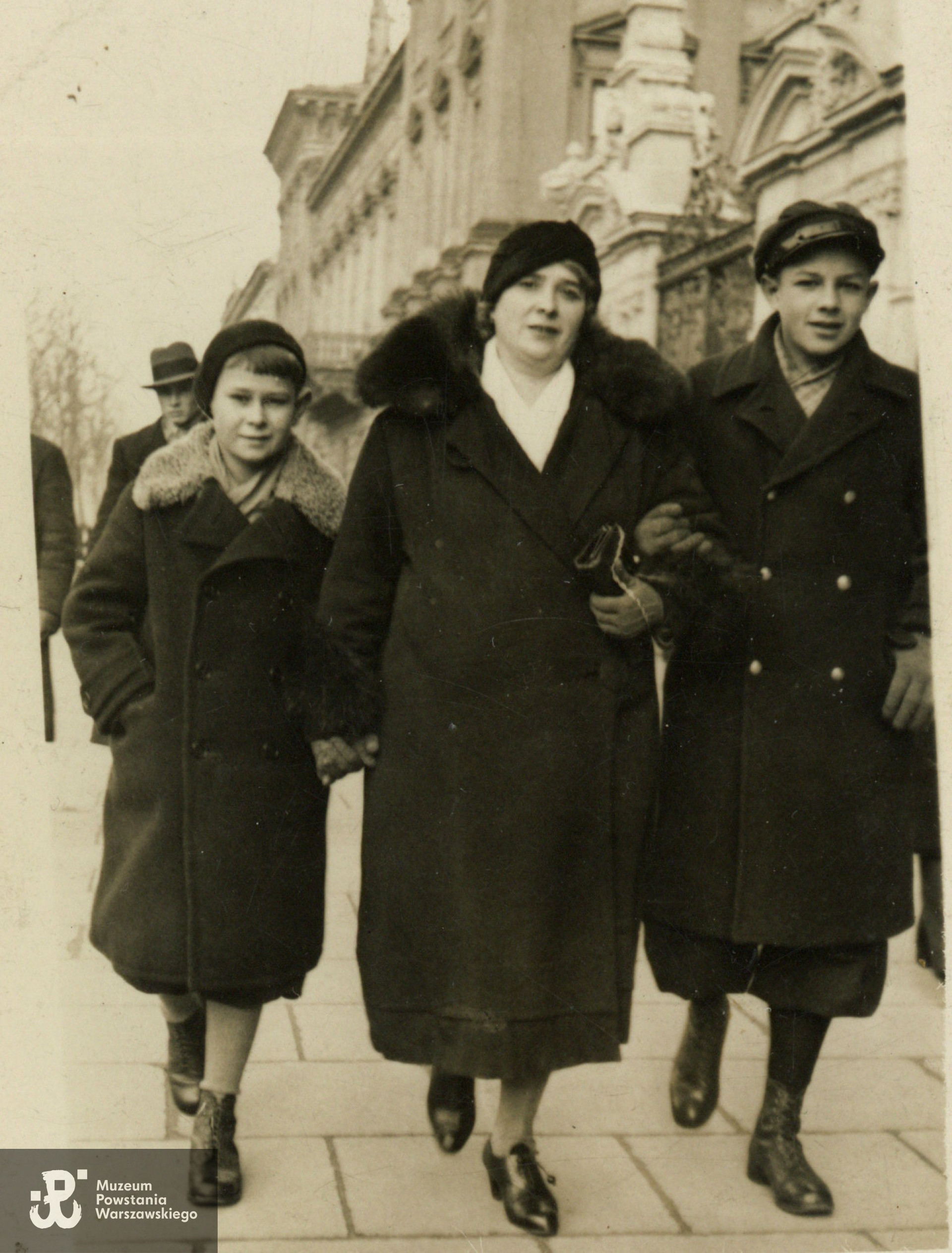 Lech (z lewej) i Jerzy (po prawej) Naumowscy z matką Fyderyką. Warszawa, ul. Krakowskie Przedmieście, lata 30-te XX w. W tle widoczna Brama Główna Uniwersytetu Warszawskiego. Fot. z archiwum rodzinnego  p. Lecha Naumowskiego