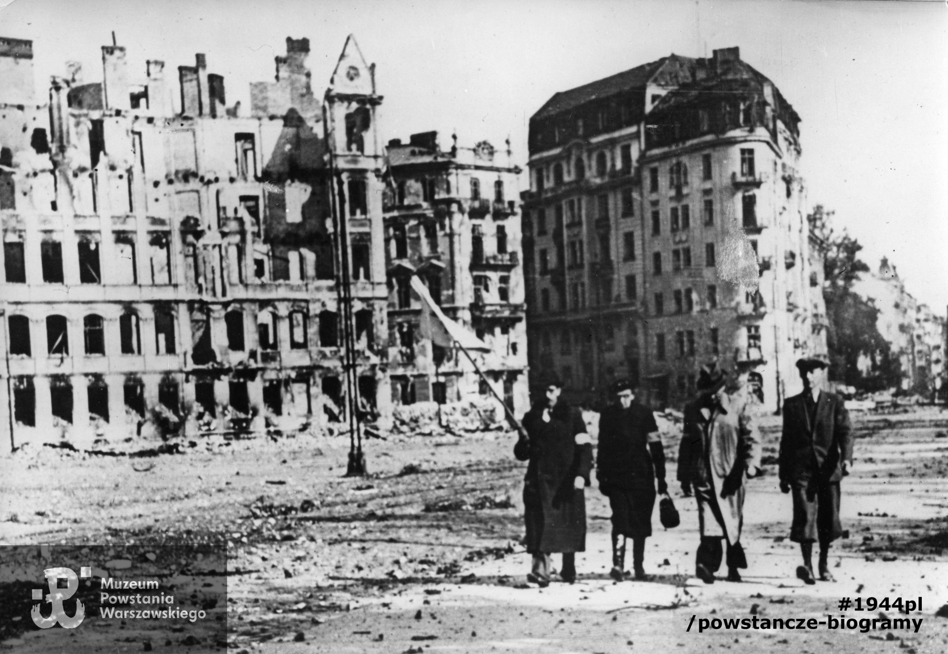 Fotografia z Powstania Warszawskiego. Śródmieście Południowe. Parlamentariusze polscy na ulicy 6 Sierpnia (obecnie Nowowiejska) zmierzający na pertraktacje w sprawie kapitulacji Powstania. Od lewej: z białą flagą dr Hieronim Bartoszewski, Maria hrabina Tarnowska, ppłk dypl. Bohdan Zieliński „Tytus Barski”, por. Alfred Korczyński „Sas”, fot. NN, Warszawa, 29 września 1944 r. Fot. ze zbiorów Muzeum Powstania Warszawskiego, sygn. MPW-IP/8661
