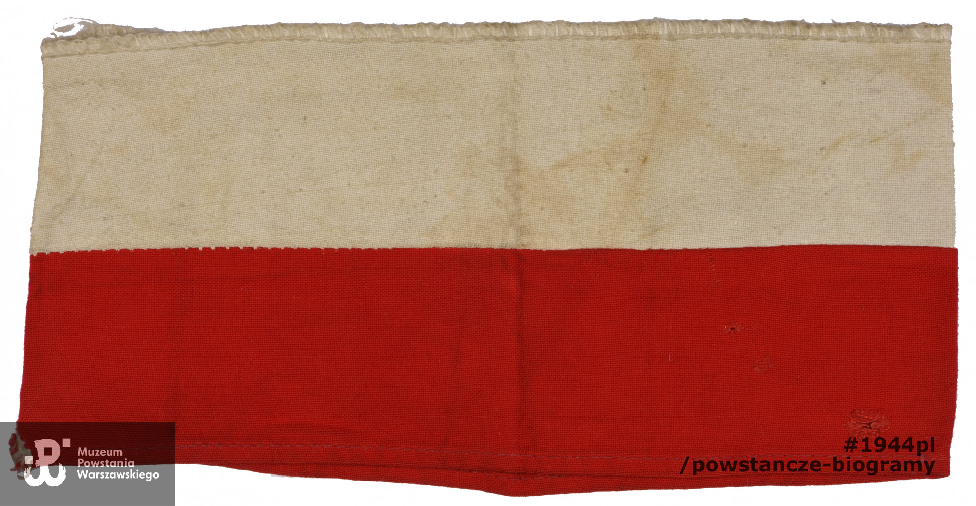 Biało-czerwona opaska powstańcza, należąca do Ireny Adamskiej ps. "Ina", "Irena" w czasie Powstania Warszawskiego pełniącej służbę jako sanitariuszka w IV zgr. "Gurt"  w punkcie sanitarnym przy ul. Sosnowej 8, a następnie w szpitalu polowym przy ul. Złotej 22. Ze zbiorów Muzeum Powstania Warszawskiego,  sygn. MPW-M/2859 (P6842/09), dar p. Jolanty Grabowskiej