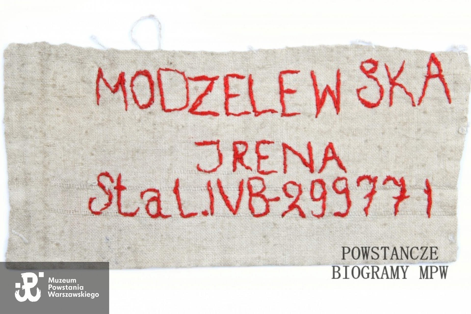 Należąca do Ireny Modzelewskiej, sanitariuszki w szpitalu na ul. Poznańskiej 11 naszywka  z obozu Zeithain,filii obozu w Mühlberg. Biała, prostokątna naszywka wykonana z  płótna z wyhaftowanym czerwoną nicią napisem: <i>Modzelewska Irena Stal.IVB - 299771</i>. Ze zbiorów Muzeum Powstania Warszawskiego