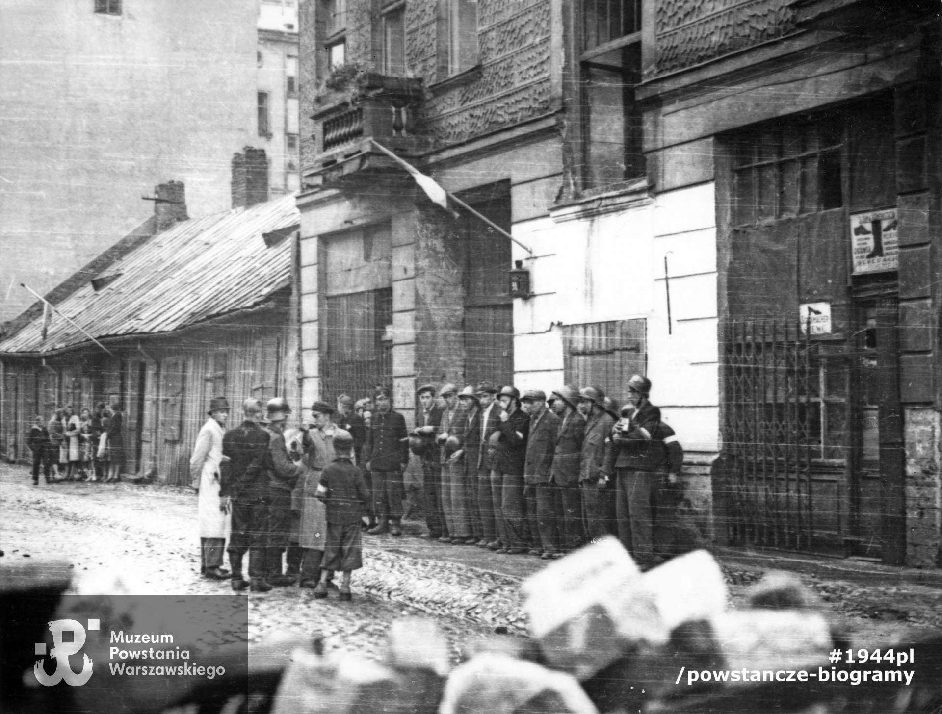 Fotografia z Powstania Warszawskiego,  3 sierpnia 1944. Zbiórka oddziału powstańczego pod kamienicą Pańska 105. Ujęcie od strony ul. Wroniej w kierunku południowo-wschodnim. Po lewej ściana szczytowa domu Pańska 101 i drewniany, parterowy domek Pańska 103. W pierwszym rzędzie pod ścianą ósmy od lewej w kaszkiecie strz. Ferdynand Onufrowicz „Dąb” (identyfikacja dokonana wyłącznie przez rodzinę Poległego, w zbiorach MPW ww. powstaniec nie jest rozpoznany). Autorem zdjęcia jest Stefan Bałuk „Kubuś”.  Fot ze zbiorów Muzeum Powstania Warszawskiego, sygn. MPW-IK/1304