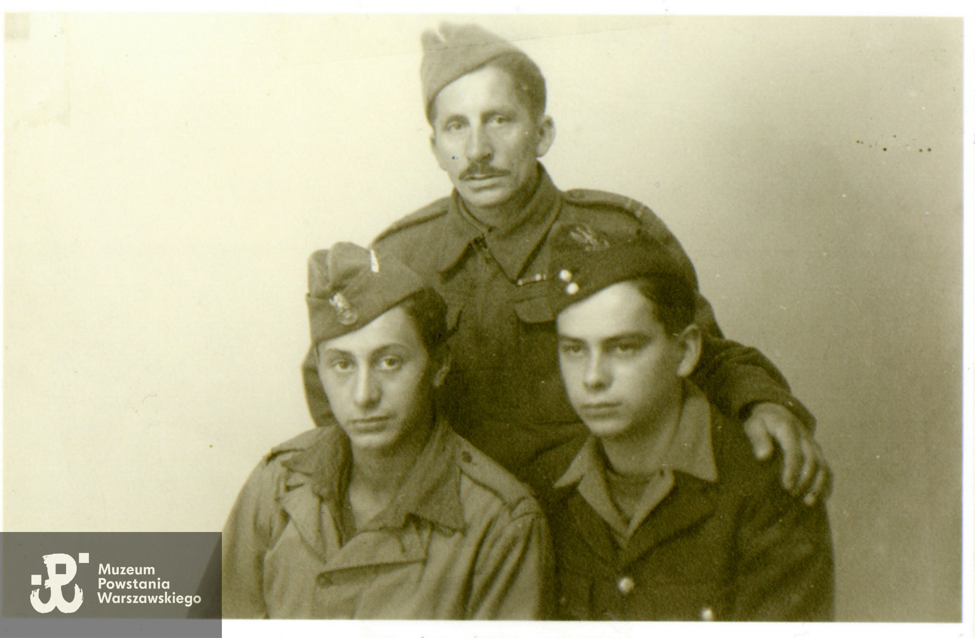 Fotografia wykonana w Northeim (Dolna Saksonia, Niemcy), dn. 27.06.1945 r.   przedstawiająca byłych żołnierzy 8. kompanii batalionu „Kiliński” (dawny Kedyw „Kolegium C”). Na dole od lewej: strz. Mieczysław Danis ps. Olgierd i Ryszard Tadeusz Szymczak ps. Czarny. Nad nimi kpr. Walenty Danis "Zenon" (ojciec Mieczysława Danisa).  Fot. udostępnił p. Mirosław Szymczak, syn Ryszarda Szymczaka „Czarnego".