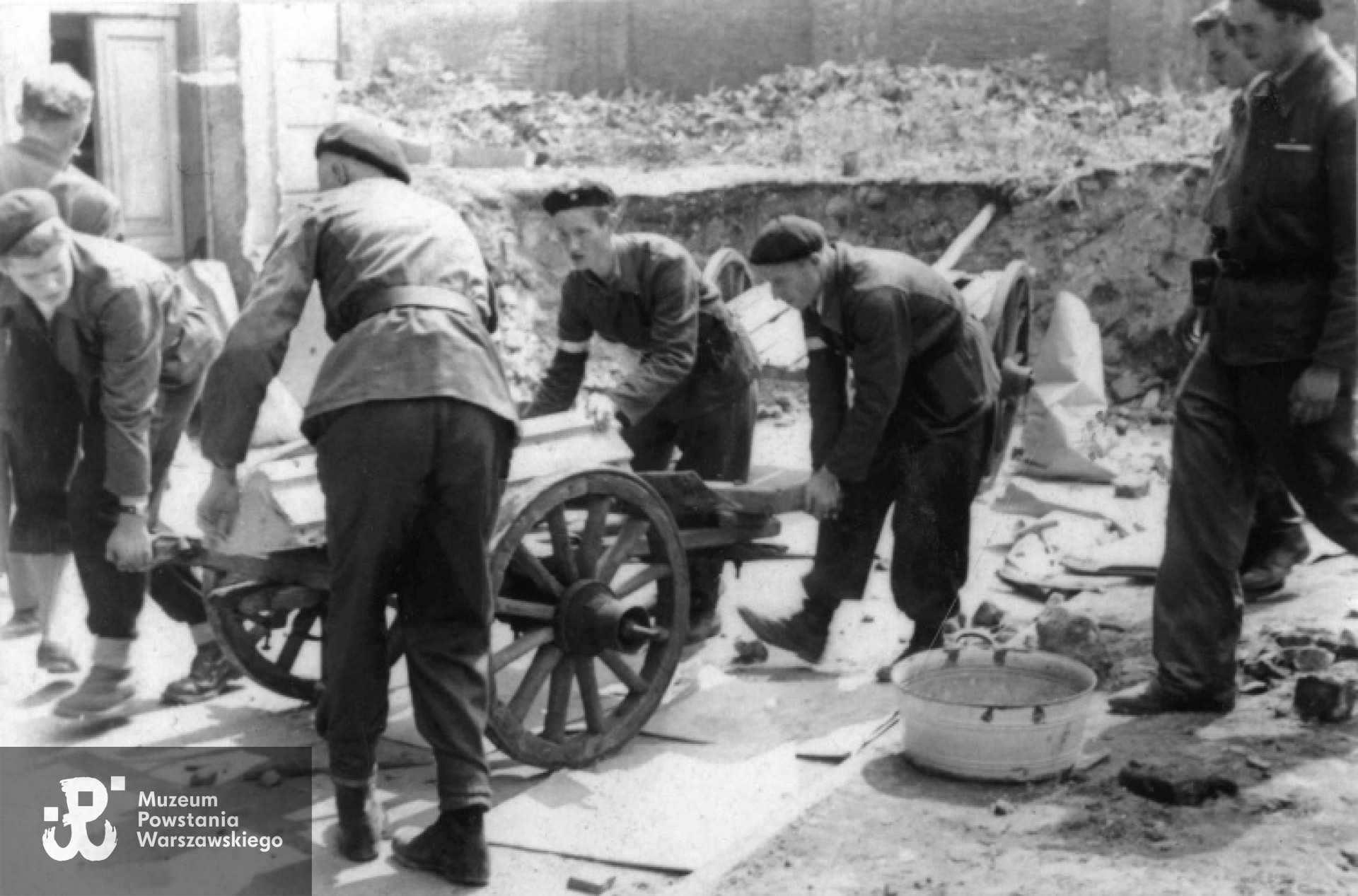 Pogrzeb nieznanego powstańca na tyłach budynku kwatery plutonu I  kompanii  szturmowej "Stefan", gruzowisko po kinie "Capitol" od ul. Zielnej. Na zdjęciu II od prawej "Krystyn" ( K. Plewko), NN, kpr. pchor. "Jastrząb" (Władysław Rudziński), pozostałe osoby nieznane. Fot. zbiory MPW