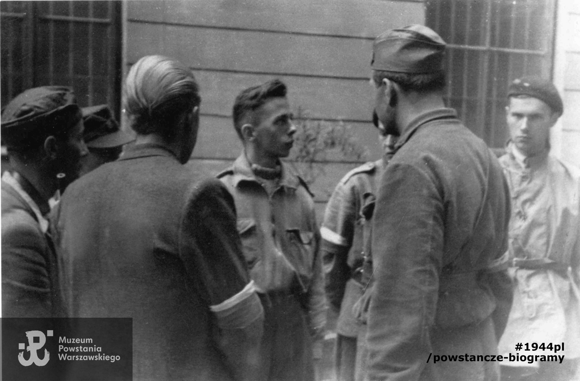 Podwórko kamienicy Marszałkowska 125 - rozmowa por. "Słonia" (Oskar Szmidt) d-cy I plutonu, poległego 4.09.1944 na Szpitalnej 4, z podwładnymi : stoją od lewej - kpr. "Happy" ( Zbigniew Zawadzki), NN, NN, kpr. pchor. "Krystyn" (Krystyn Plewko). Porucznik "Słoń" - tyłem, VI od lewej.  Pozostałe osoby nieznane. Fot. zbiory MPW