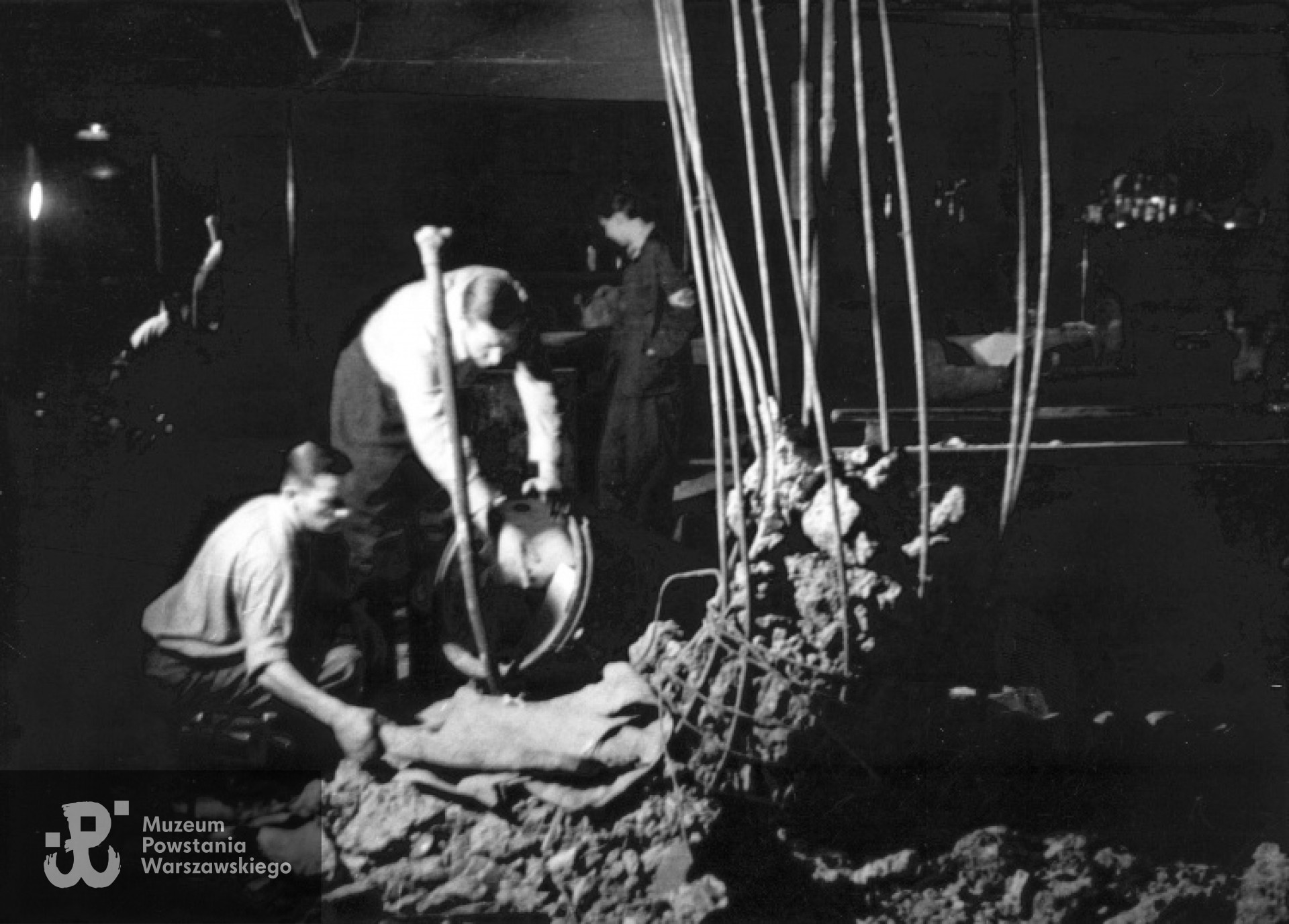 Jw. Pirotechnicy rozbrajający niewybuch pocisku, wystrzelonego z moździerza Karl Mörser, w restauracji "Adria" przy ulicy Moniuszki 10. Fotografia  autorstwa Eugeniusza Lokajskiego „Broka”, zbiory Fototeki  MPW, sygn.  MPW-IN/395.  Prawa autorskie: MPW