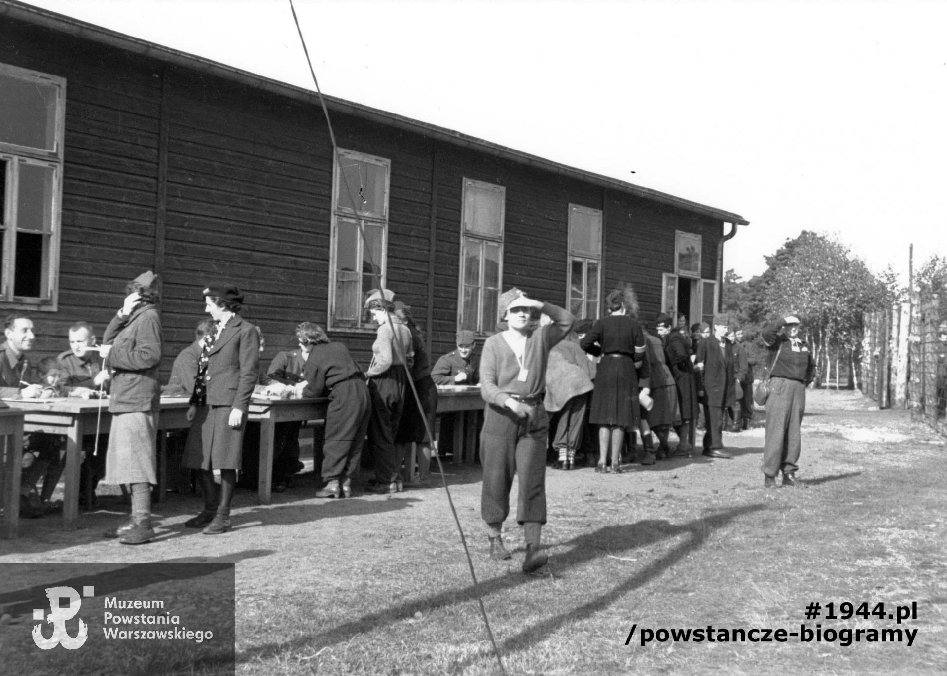 Fotografia z obozu jenieckiego Stalag XI B w Fallingbostel, 10.10.1944 r.  Wydawanie numerów jenieckich przy baraku obozowym. Na pierwszym planie strz. Wiktoria Darmosz "Adusia". Fot. ze zbiorów Muzeum Powstania Warszawskiego, sygn. MPW-IP/4476