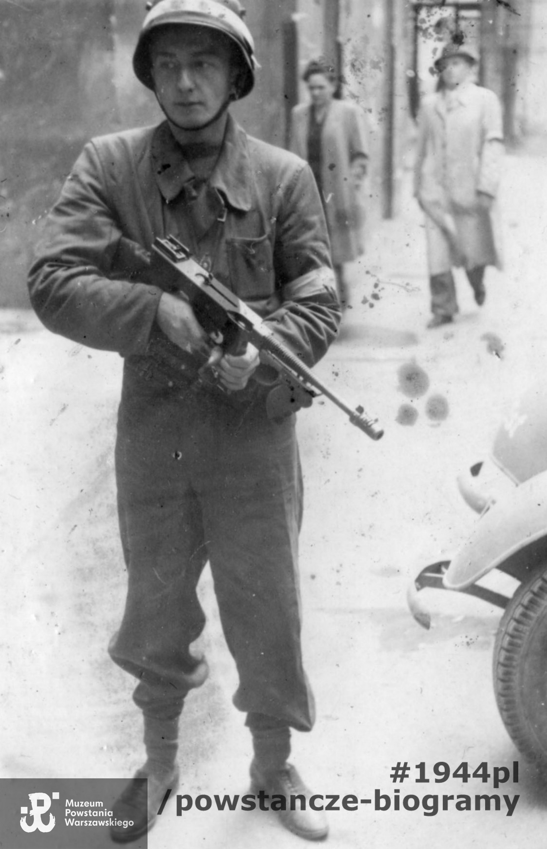 Fotografia z Powstania Warszawskiego. Śródmieście Północne. Kpr. pchor. Włodzimierz Green "Gazda" z II plutonu Oddziału Osłony Kwatery Głównej Okręgu Warszawskiego AK z amerykańskim pistoletem maszynowym Thompson wz 1928 na podwórzu kamienicy braci Bachrachów przy ul. Świętokrzyskiej 36/38/40. Ze zbiorów Muzeum Powstania Warszawskiego, sygn. MPW-IP/7010. 