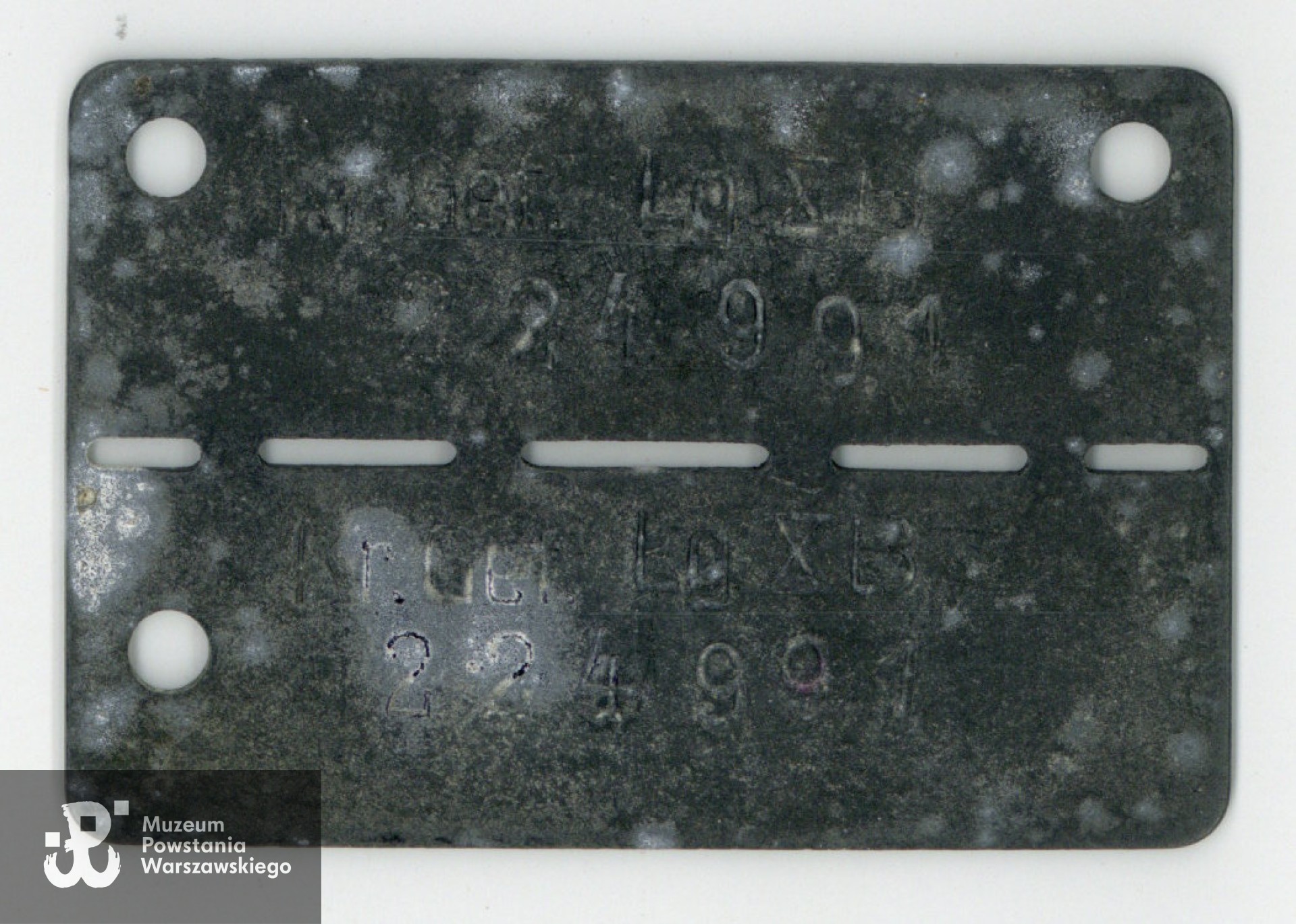 Należąca do Aleksandra Taffa blaszka jeniecka - nieśmiertelnik obozowy. Ze zbiorów rodzinnych, udostępniła wnuczka Powstańca, p. Paulina Taff. Skany wykonano w Muzeum Powstania Warszawskiego, 06/2024