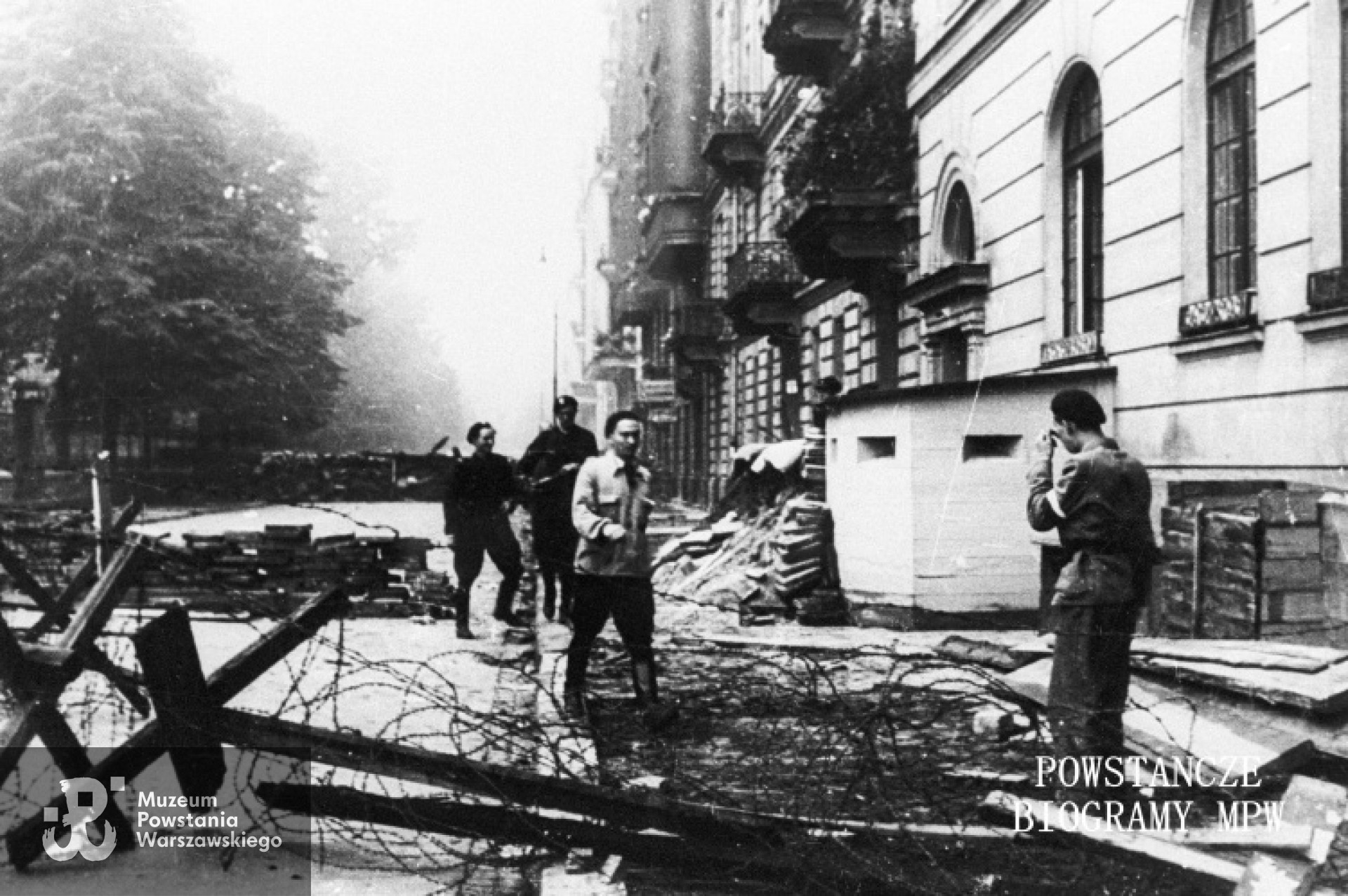Fotografia  z okresu Powstania Warszawskiego autorstwa Tadeusza Bonclera: ulica Noakowskiego w pobliżu wylotu na ul. 6 Sierpnia i Lwowską. Po prawej fragment gmachu gimnazjum Staszica, w którym znajdował się zdobyty niemiecki szpital polowy z dobudowanym przy wejściu bunkrem. Dalej kamienice pod nr: 8, 10 i 12. Na ulicy pierwsze powstańcze zasieki z drutu kolczastego. Ze zbiorów Muzeum Powstania Warszawskiego, sygn. MPW-IN/4351