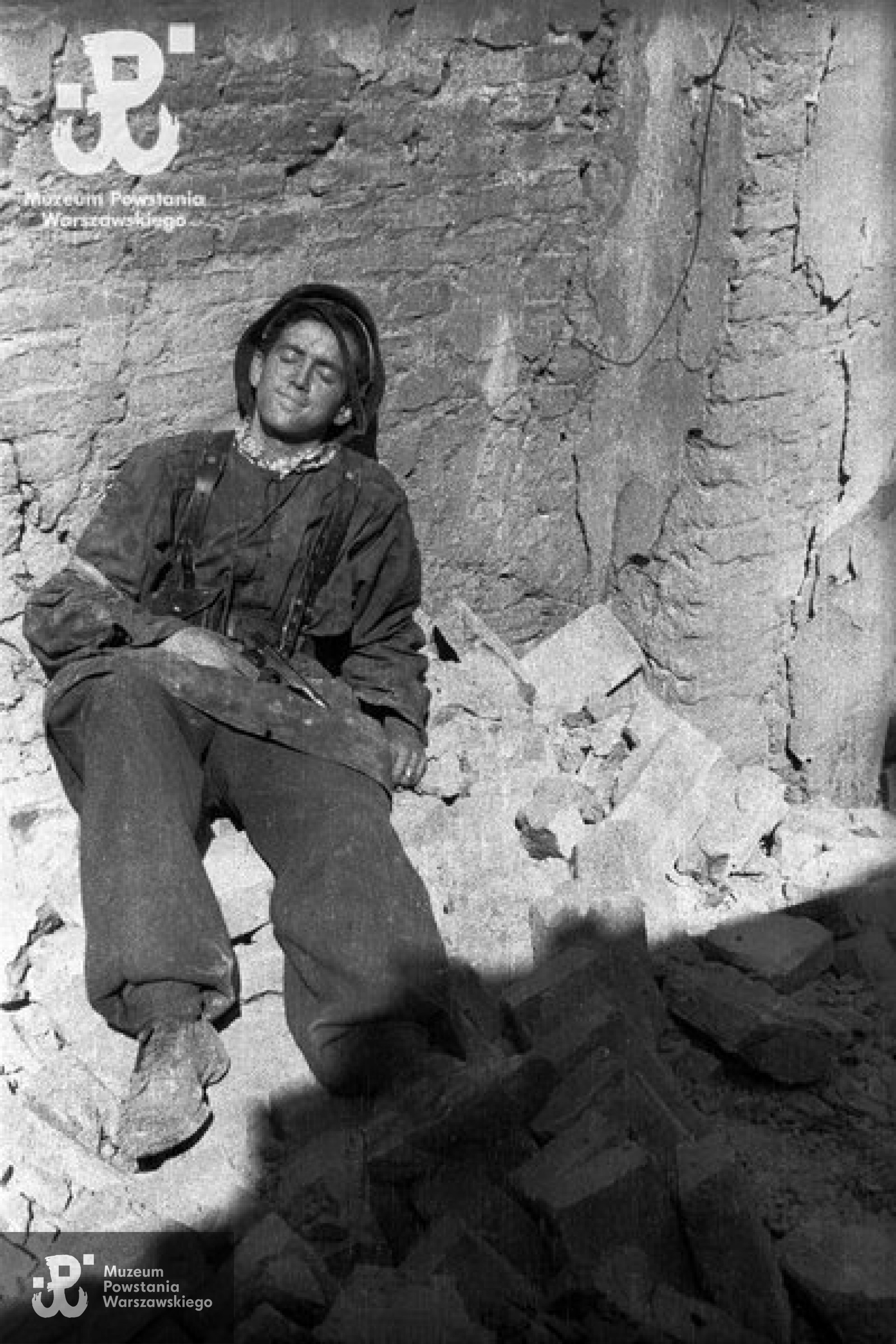 Fotografia z Powstania Warszawskiego. Stare Miasto. Kpr. Jerzy Sikorski „Sixton” odpoczywający w pobliżu stanowiska na ulicy Ślepej.Autorem zdjęcia jest Wiesław Chrzanowski „Wiesław”. Ze zbiorów Muzeum Powstania Warszawskiego, sygn. MPW-IN/3244