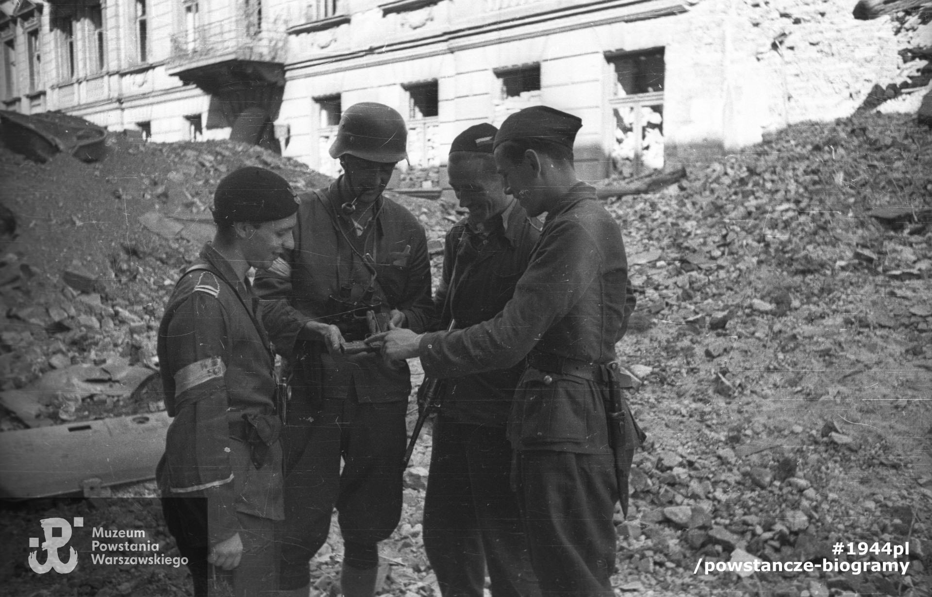 Fotografia z Powstania Warszawskiego. Śródmieście Północne. Żołnierze 569 plutonu 2. Harcerskiej Baterii Artylerii Przeciwlotniczej "Żbik" Zgrupowania "Gurt" oglądający zdobyczny pistolet przy ul. Chmielnej 61. Stoją od lewej: kpr. pchor. Adam Bóbr "Jaxa", plut. Włodzimierz Dąbkowski "Romer", sierż. Zygmunt Klimowicz "Neron" (przed powstaniem żołnierz AL) i  Marek Raczyński "Żwir-Podziemski".  Autorem zdjęcia jest Joachim  Joachimczyk. Zbiory Muzeum Powstania Warszawskiego, sygn.  MPW-IN/10419