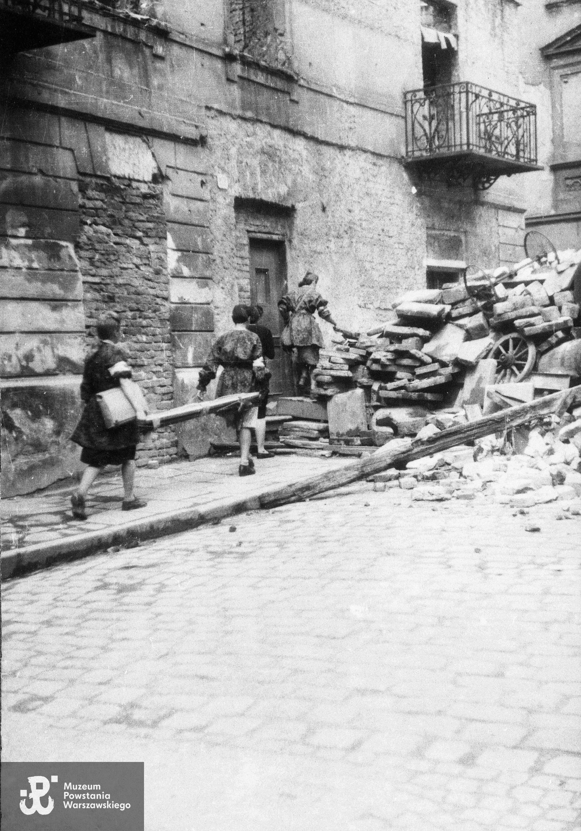 Fotografia z Powstania Warszawskiego. Patrol sanitarny przechodzący przez barykadę na ul. Piekarskiej. Na dalszym planie po lewej, za kamieniczką Piekarska 18, wylot ul. Rycerskiej. Autorem zdjęcia jest Jerzy Chojnacki "Chojna". Zdjęcie ze zbiorów Muzeum Powstania Warszawskiego, sygn. MPW-IH/2233. Według informacji przekazanych przez wnuka Wiesławy Kamper-Gliszczyńskiej przypuszczalnie pierwszą z dziewcząt wspinających się na barykadę jest "Sławka".