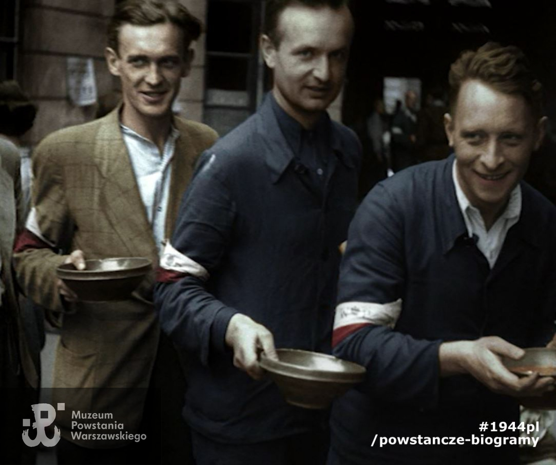 Kadr kolorowy z filmu Powstanie Warszawskie. Stołówka powstańcza na podwórzu kamienicy przy ul. Szpitalnej 8. Od lewej: kpr. pchor. Bernard Wojciech Mencel „Paweł”, członek patrolu megafonowego „Chwaty” (poległ 13.09.1944 r. przy ul. Marszałkowskiej),  por. Józef Marian Sosnowski, ps. Brzeziński, Tadeusz Mikulski „Krasicki”. Zdjęcie filmowe z okresu Powstania. Ze zbiorów Muzeum Powstania Warszawskiego.