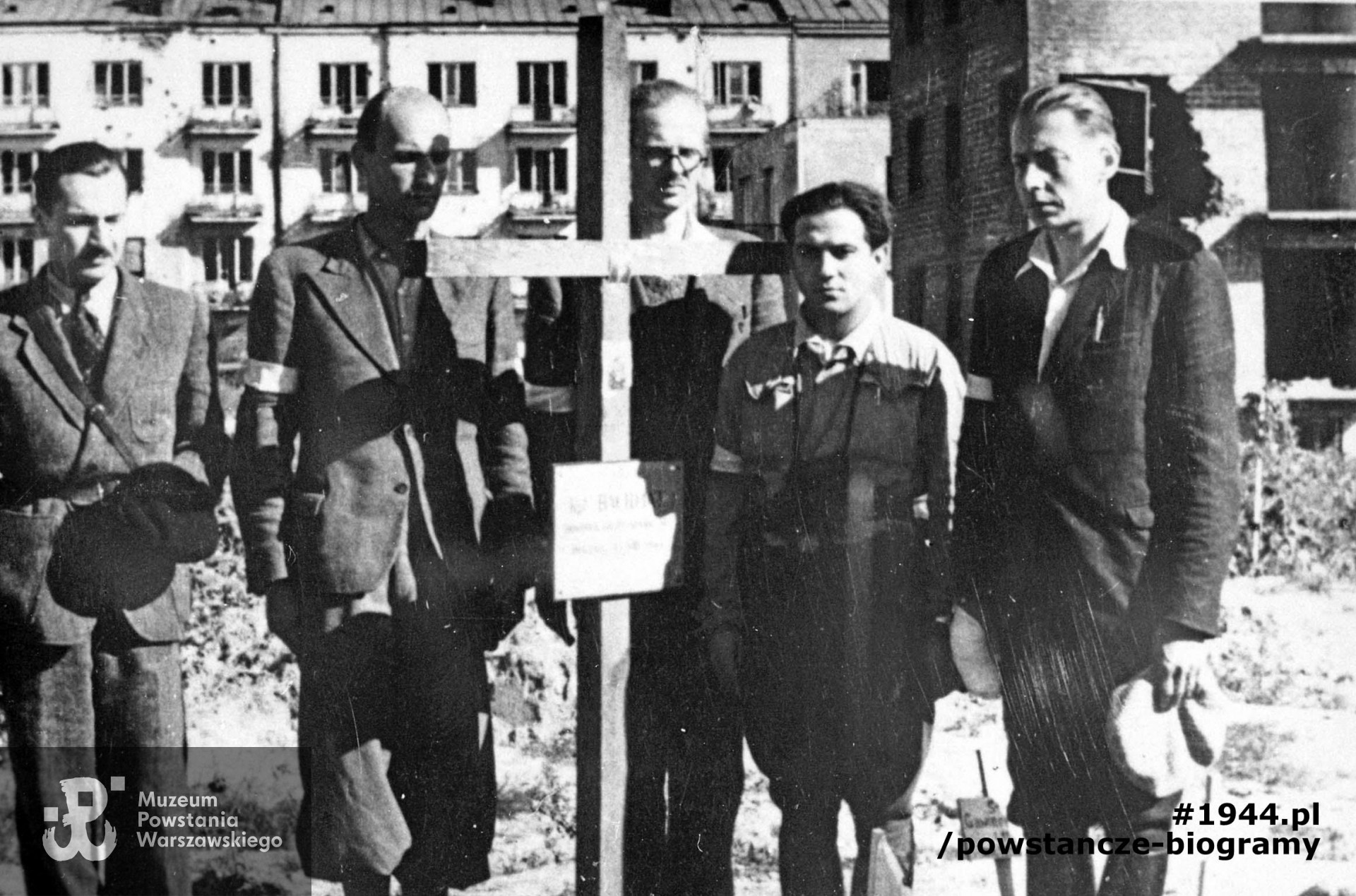 Zdjęcie filmowe z Powstania Warszawskiego. Mokotów, cmentarz powstańczy przy Szpitalu Elżbietanek w rogu ulic Goszczyńskiego i Tynieckiej. W tle budynki Odyńca 11-13. Grupa powstańców z Grupy Artyleryjskiej "Granat" przy grobie dowódcy, mjr art. Józef Szyszko "Bachmat", który zginął 13 sierpnia. Stoją od lewej: ppor. Stanisław Saryusz-Wolski "Szrapnel", kpr. pchor. Zbigniew Grochowski "Roma" "Mazur" (?), por. Adam Jastrzębski "Różan", ppor. Waldemar Olszewski "Waldemar", ppor. Stanisław Kietliński "Hel". Ze zbiorów Muzeum Powstania Warszawskiego, sygn. MPW-IH/1215