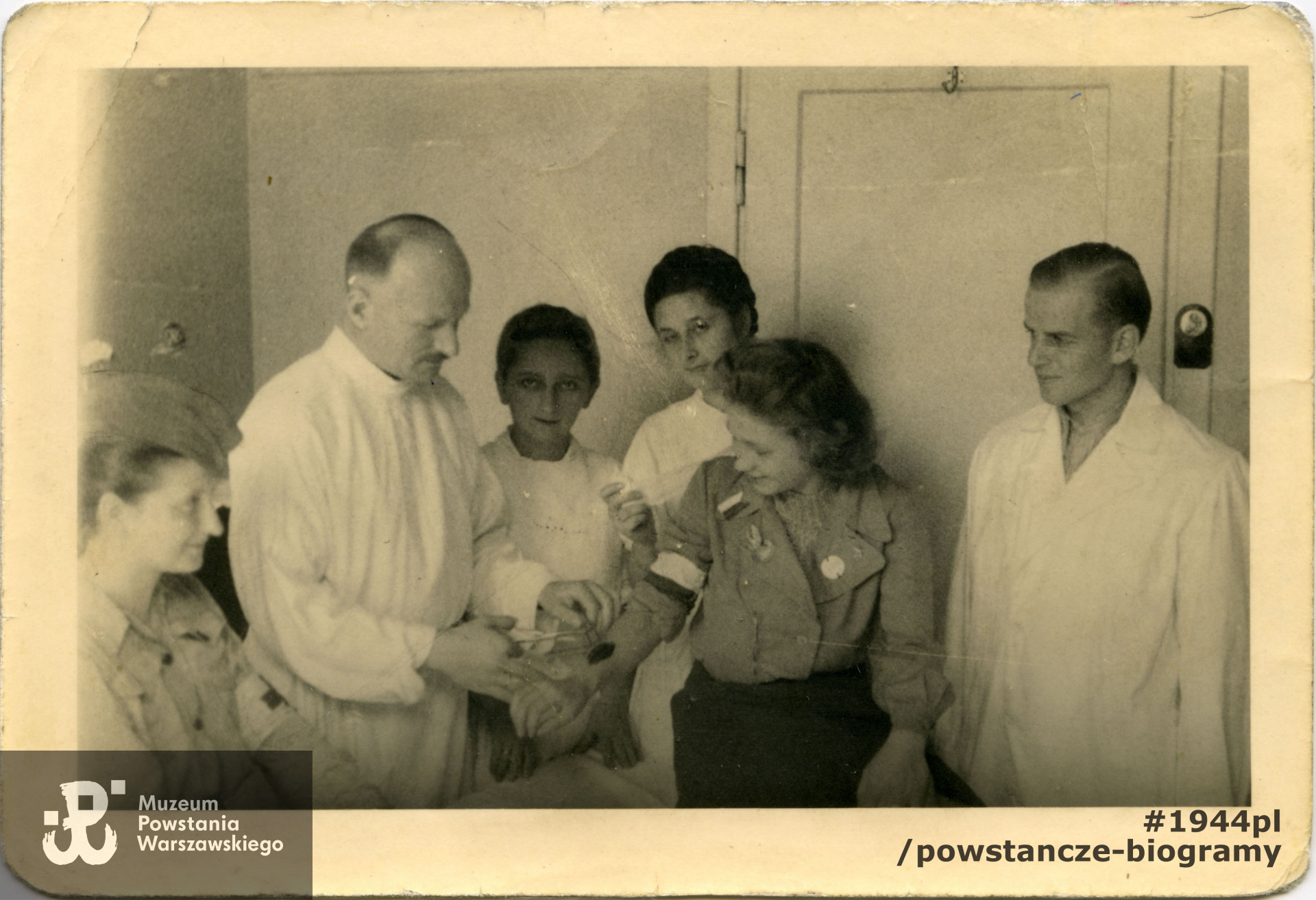 Fotografia z Powstania Warszawskiego. Powiśle. Szpital polowy w Domu Zgromadzenia Sióstr Szarytek przy ulicy Tamka 30. Doktor Jerzy Rowiński "Jurand" wyjmuje odłamek łączniczce. Obok niego po prawej stronie sanitariuszki Maria Rowińska i Barbara Szuladzińska "Wanda". Autor zdjęcia nieznany, ze zbiorów MPW, sygn. MPW-IP/2012