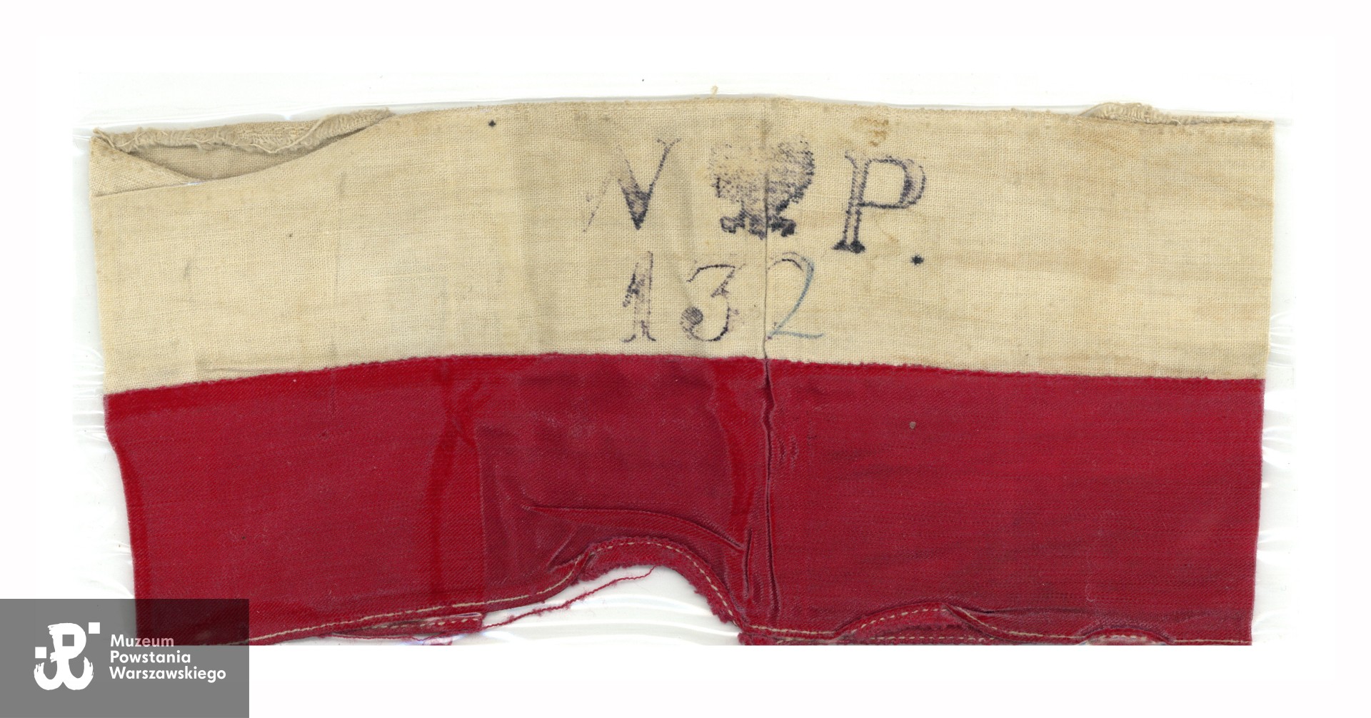 Opaska Sanitariuszki "Kasi" z numerem plutonu 132 ( I Obwód "Radwan" (Śródmieście) Warszawskiego Okręgu Armii Krajowej - V zgrupowanie "Siekiera" - 1 kompania). Ze zbiorów Muzeum Powstania Warszawskiego, dar syna