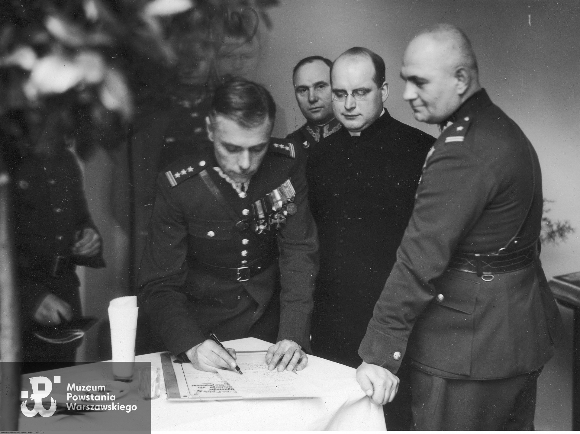 Poznań, 31 stycznia 1935 roku - Poświęcenie nowego pawilonu VII Okręgowego Szpitala Wojskowego w Poznaniu. Płk dr Teofil Kucharski wpisuje się do księgi pamiątkowej nowego szpitala. Widoczni także m.in.: ks. kapelan Franciszek Dymarski (2. z prawej) i mjr dr Longin Wałęga (1. z prawej) z korpusu sądowego.  Fot. ze zbiorów Narodowego Archiwum Cyfrowego, www.audiovis.nac.gov.pl