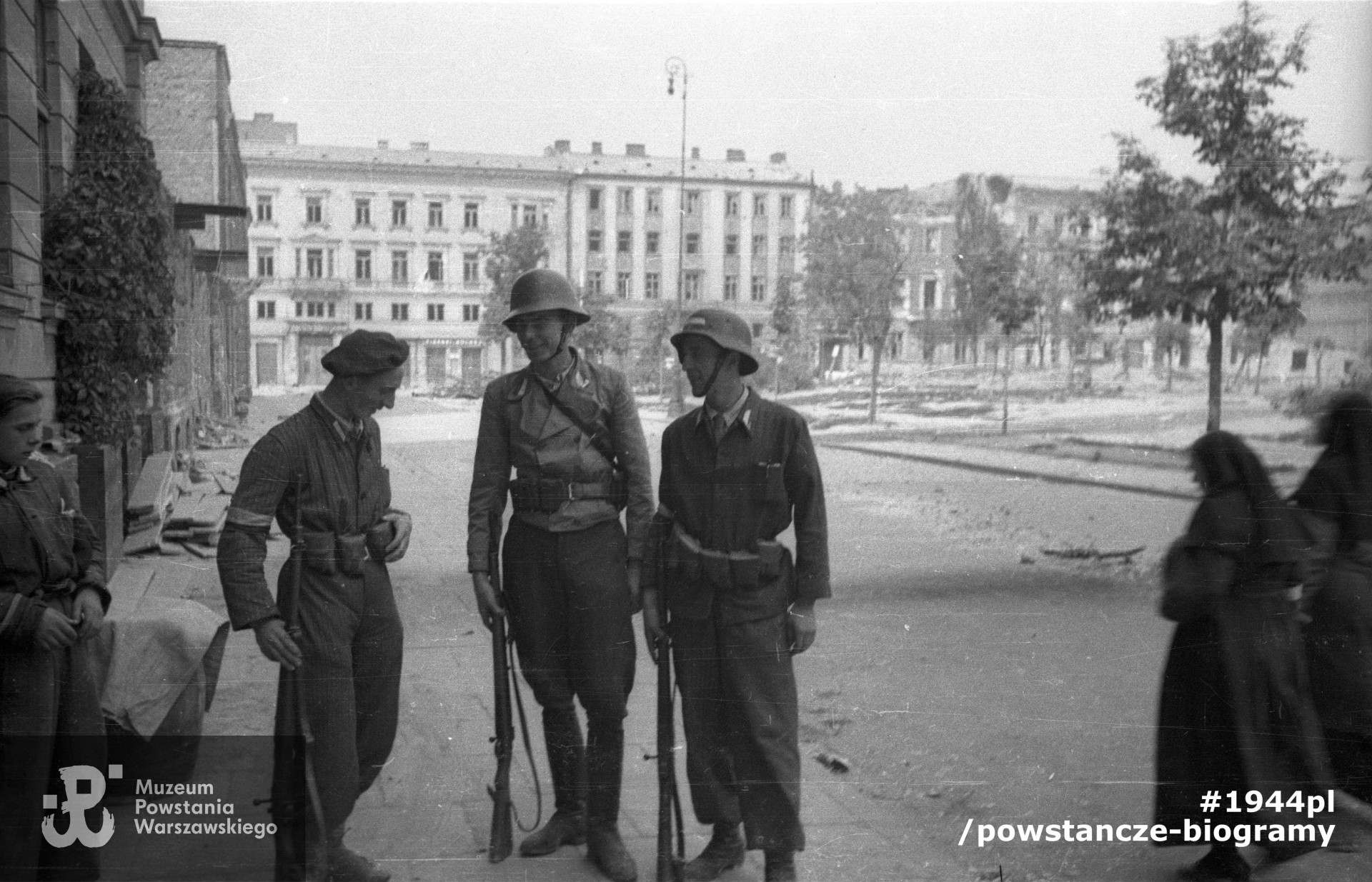 Fotografia z Powstania Warszawskiego. Śródmieście Północne. Żołnierzy 1150 plut. Zgrupowania „Bartkiewicz”  przed swoją kwaterą na pl. Dąbrowskiego 5. Autorem zdjęcia jest Joachim Joachimczyk. Fot. ze zbiorów Muzeum Powstania Warszawskiego