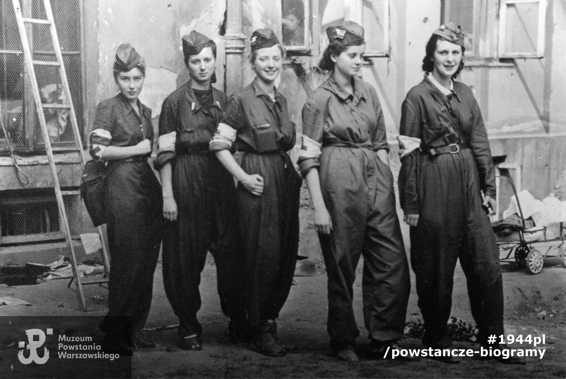 Izabela Kunińska-Zachwatowicz  z d. Sztos ps. "Ryś" (na zdjęciu pośrodku, z rękami w kieszeniach) z koleżankami podczas Powstania Warszawskiego.Stoją od lewej: Barbara Przygodzka "Żabka", Alina Kłopotowska " Pantera", Izabela Sztos-Zachwatowicz " Ryś", Halina Przybylska " Misia" i Wiera Dudzińska " Angora".  Fot. ze zbiorów Muzeum Powstania Warszawskiego, sygn. MPW-IP/5773. Ujęcie tożsame: MPW-IP/2081