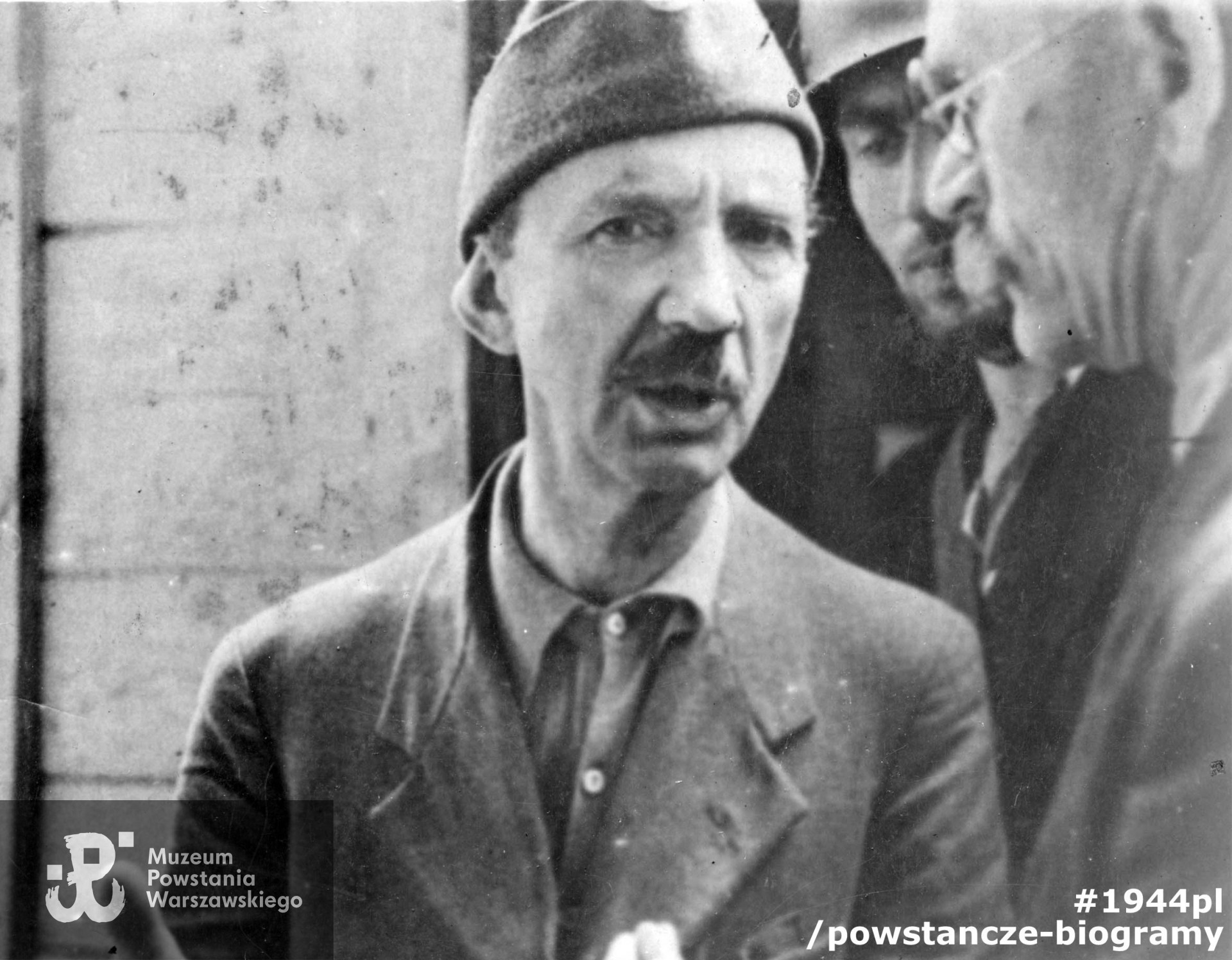 Fotografia z Powstania Warszawskiego. Śródmieście Północne. Ppłk. Jan Szypowski "Leśnik" przed gmachem Sądu Grodzkiego na ul. Ogrodowej. Po prawej mjr Adolf Łojkiewicz "Ryś" (w okularach), z tyłu pchor. Marian Gorzkowski "Szary", zbiory Muzeum Powstania Warszawskiego MPW-IK/1324