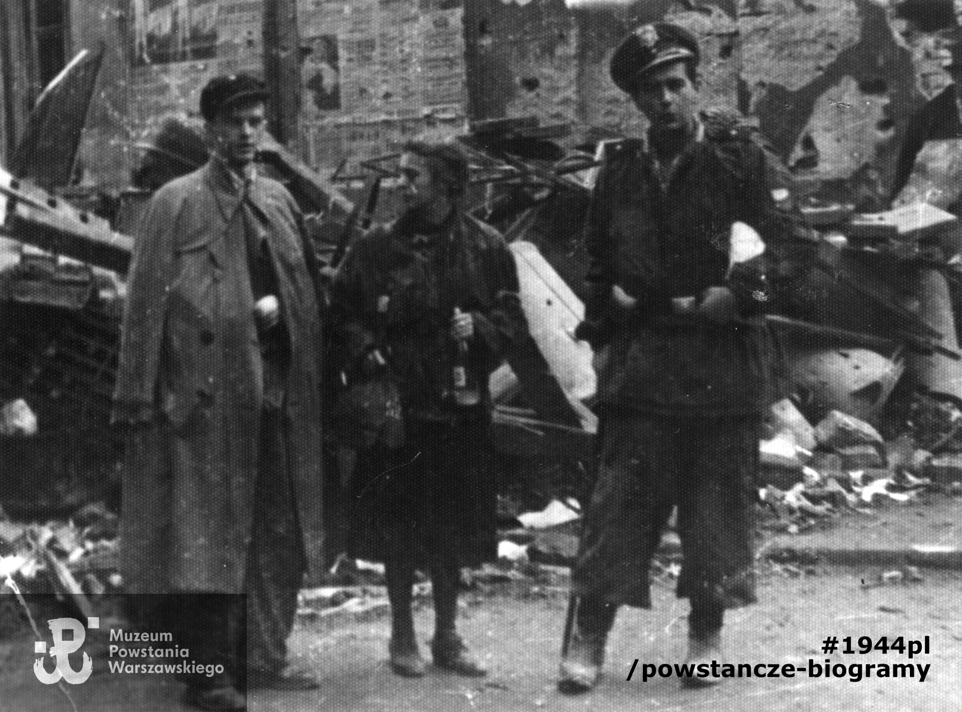 Fotografia z Powstania Warszawskiego, przedstawiająca żołnierzy batalionu Chrobry I we wrześniu 1944 roku na ul. Chmielnej. Stoją od lewej: pchor. Zbigniew Januszkiewicz,[nieczytelne] 2. sanitariuszka Baśka Januszkiewicz, Jerzy Piszczek"Jeż".   Fot.  ze zbiorów Muzeum Powstania Warszawskiego, sygn. MPW-IP/5747