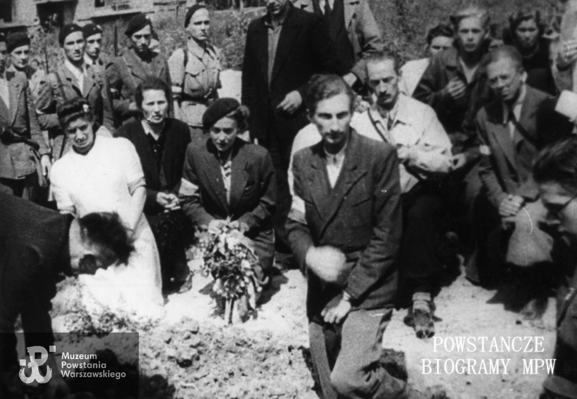 Zdjęcie filmowe z Powstania Warszawskiego autorstwa Romana Banacha ps. "Świerk". Mokotów, cmentarz powstańczy przy Szpitalu Elżbietanek w rogu ulic Goszczyńskiego i Tynieckiej. Grupa powstańców na pogrzebie sanitariuszki Anny Habrowskiej "Marii" z plutonu 1110 dywizjonu "Jeleń". Na pierwszym planie kpr. pchor. Andrzej Bontemps "Mnich", za nim w w jasnej kurtce rtm. Lech Głuchowski "Jeżycki" dowódca "Jelenia". Z kwiatami sanitariuszka Alina Ciembroziewicz-Zabiełło "Alina". Od prawej profilem st. ułan pchor. Andrzej Czernik "Cebion", w okularach st. ułan pchor. Tadeusz Doberski "Dobnia". Z tyłu czwarty od lewej st. strz. pchor. Józef Ruszczyński "Lis", szósty st. ułan pchor. Włodzimierz Drecki "Kawka". Fot. ze zbiorów Muzeum Powstania Warszawskiego, sygn. MPW-IK/1717