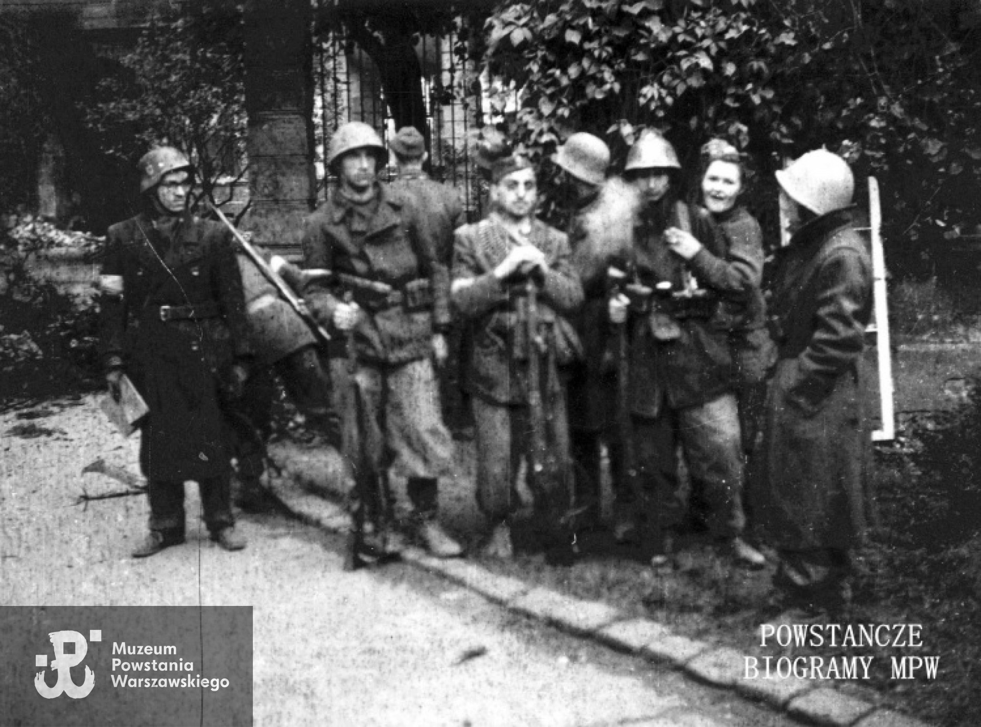 Fotografia z Powstania Warszawskiego.  Powstańcy z plutonu "Rygla" zgrupowania "Bartkiewicz" na dziedzińcu pałacyku Brzozowskich Bracka 20. Od lewej: sierż. pchor. Władysław Buksowicz "Kalinowski", NN, łączniczka Krystyna Żara "Krystyna", kpr. z cenz. Jerzy Jenike "Zwierz" (widoczny fragment głowy), strz. Antoni Bukraba "Żeglarz", st. strz. Władysław Janiszewski "Sęp", kpr. pchor. Andrzej Strawiński "Chimera", łączniczka Danuta Szczepańska-Kuczyk "Danka Biała", st. strz. Zbigniew Kurbiel "Krakus", kpr. Mieczysław Olesiński "Mały Mały". Autor zdjęcia Irena Kummant-Skotnicka "Janina". MPW - sygn.MPW-IP/3901