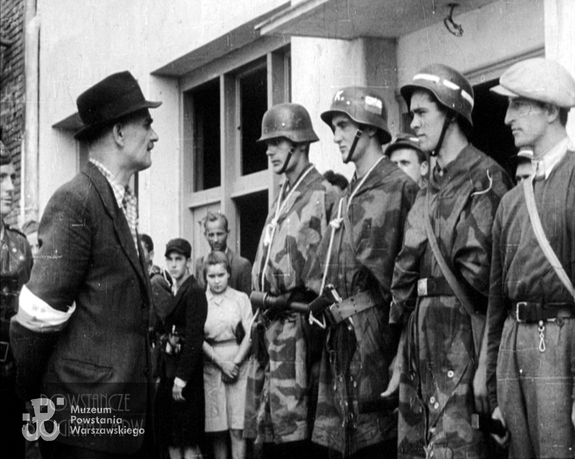 Dowódca pułku "Baszta" ppłk. Stanisław Kamiński "Daniel" (w kapeluszu) dokonuje wraz z dowódcą dywizjonu "Jeleń" rtm. Lechem Głuchowskim "Jeżyckim" przeglądu oddziałów przybyłych z Lasów Kabackich i Chojnowskich. Żołnierze od lewej: strz. Bolesław Wiewióra "Samson", strz. Józef Wilczak "Wilk", kpr. Stanisław Sekuła "Śmiały", w czapce cyklistówce kpr. pchor. Tadeusz Kozłowski "Kozak". Kadr z powstańczej kroniki filmowej / MPW