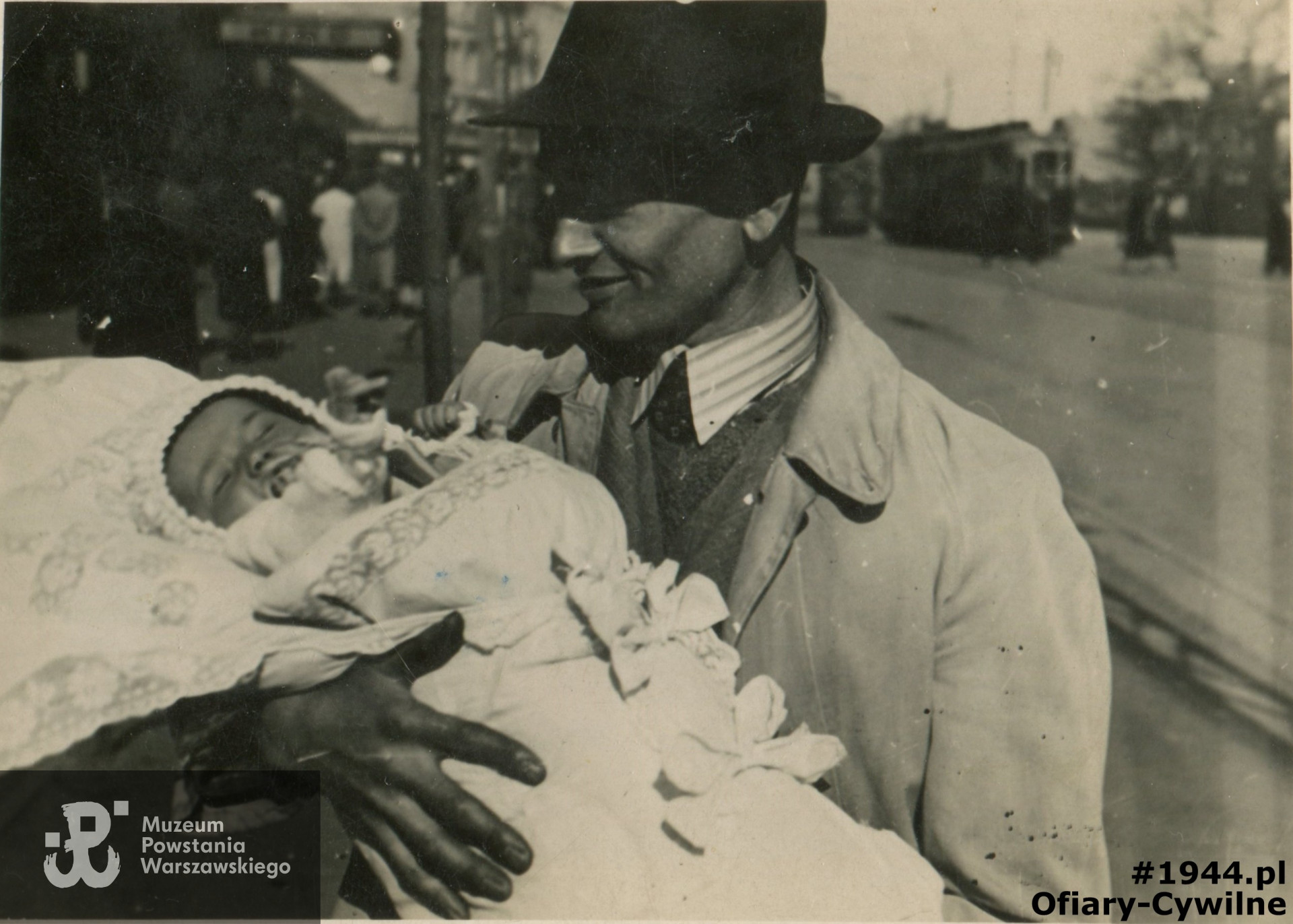 Władysław Kopczyński trzyma na rękach swoją córkę Alicje urodzoną 9 stycznia 1942 r., zdjęcie wykonane na ul. Wolskiej w tle neon kina „Italia”, zdjęcie ze zbiorów córki pani Alicji Gaik zd. Kopczyńskiej